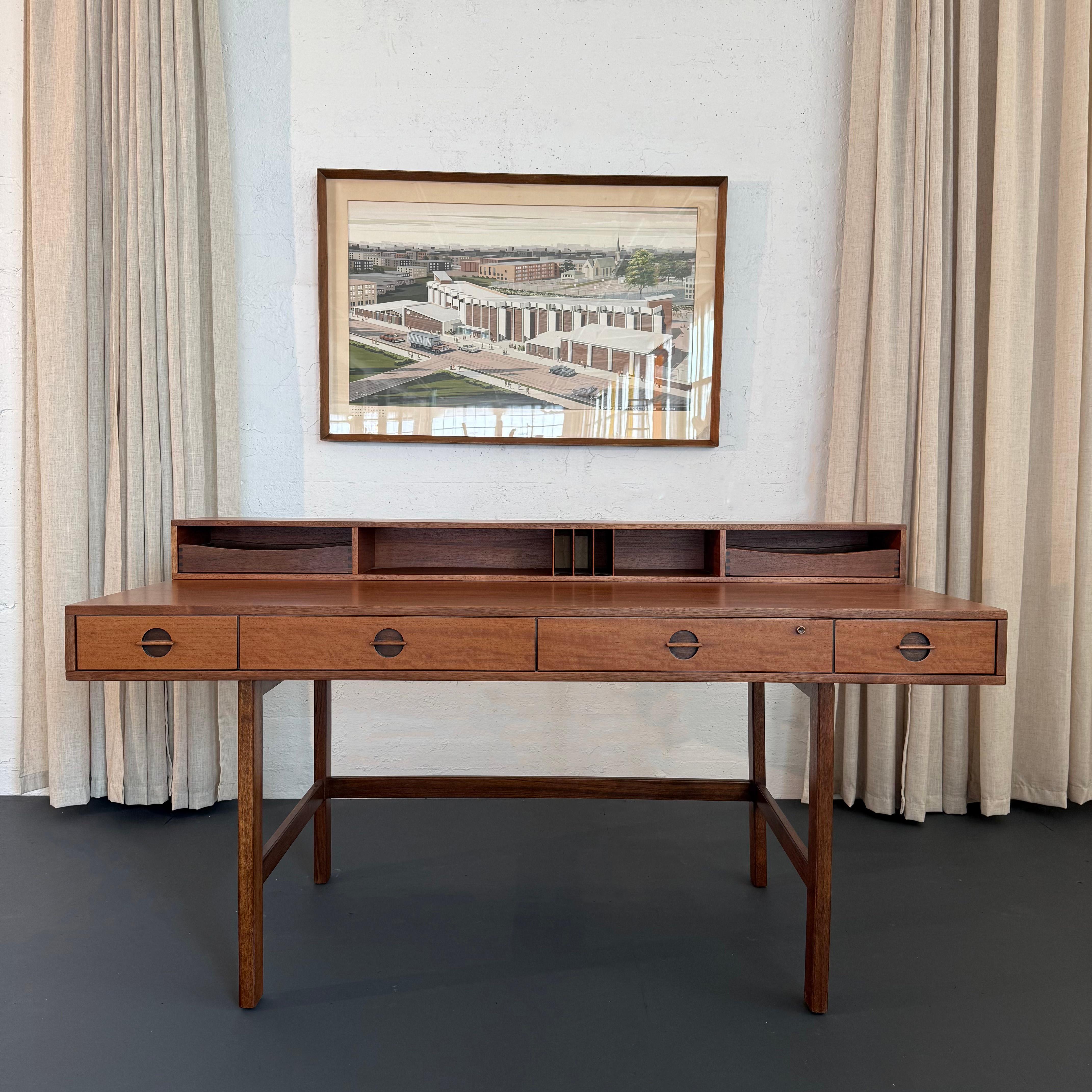 This spectacular Danish teak desk was designed circa 1960s by Peter Løvig Nielsen. The desk features stunning details throughout with beautiful teak grain, recessed circular drawer pulls and brass hinges. This ingenious design is extremely versatile