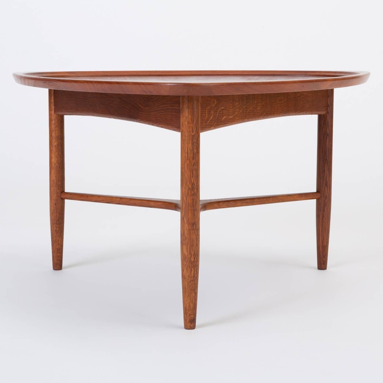 A Scandinavian Modern teak occasional table has a triangular “guitar pick” shape and three tapered dowel legs. The piece, in strong-grained teak wood, is distinguished by a recessed, Reuleaux-triangular well in its surface, and by sophisticated