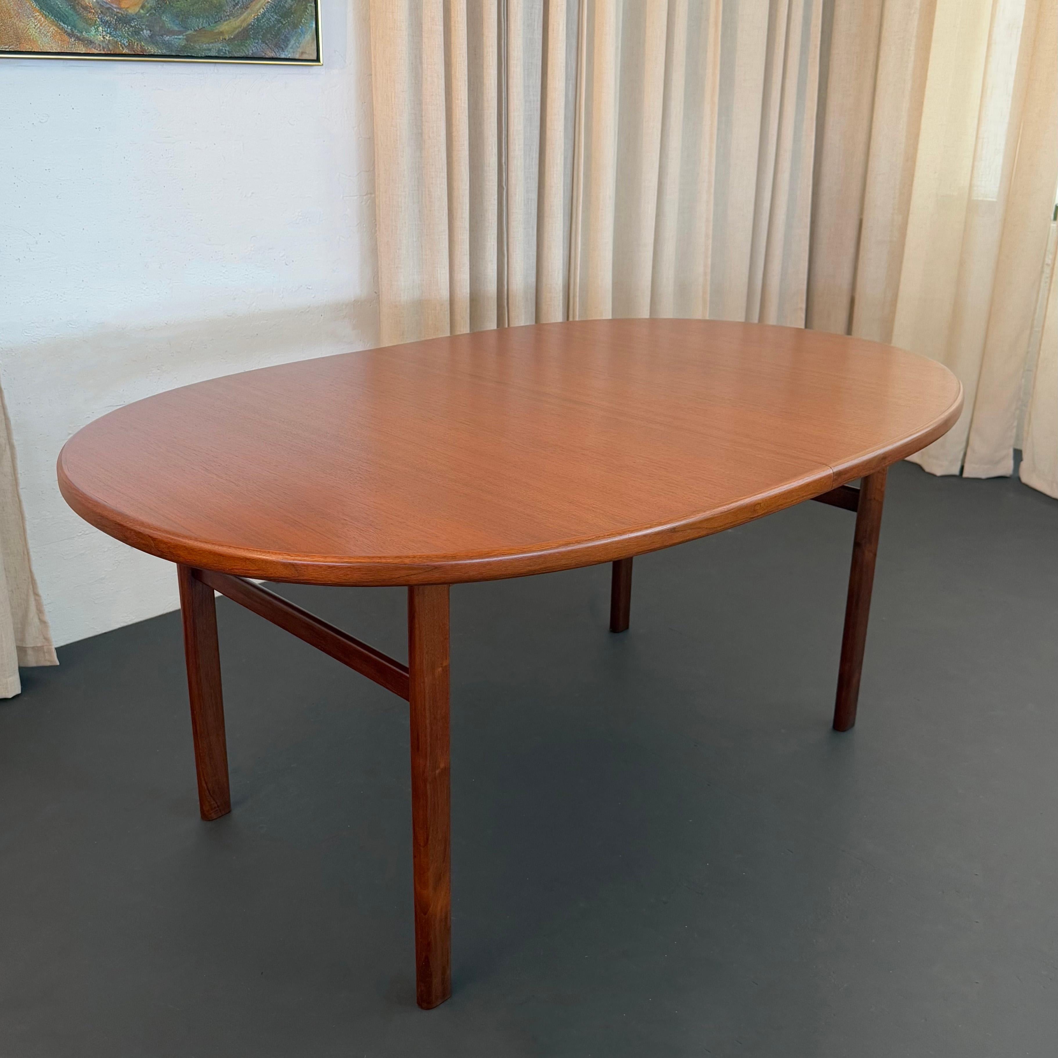 This well-built, Scandinavian Modern teak extension dining table is a study in minimal yet thoughtful design with a timeless profile. The dining table features an oblong top with banded trim and smooth rounded edges throughout. The H-style legs are