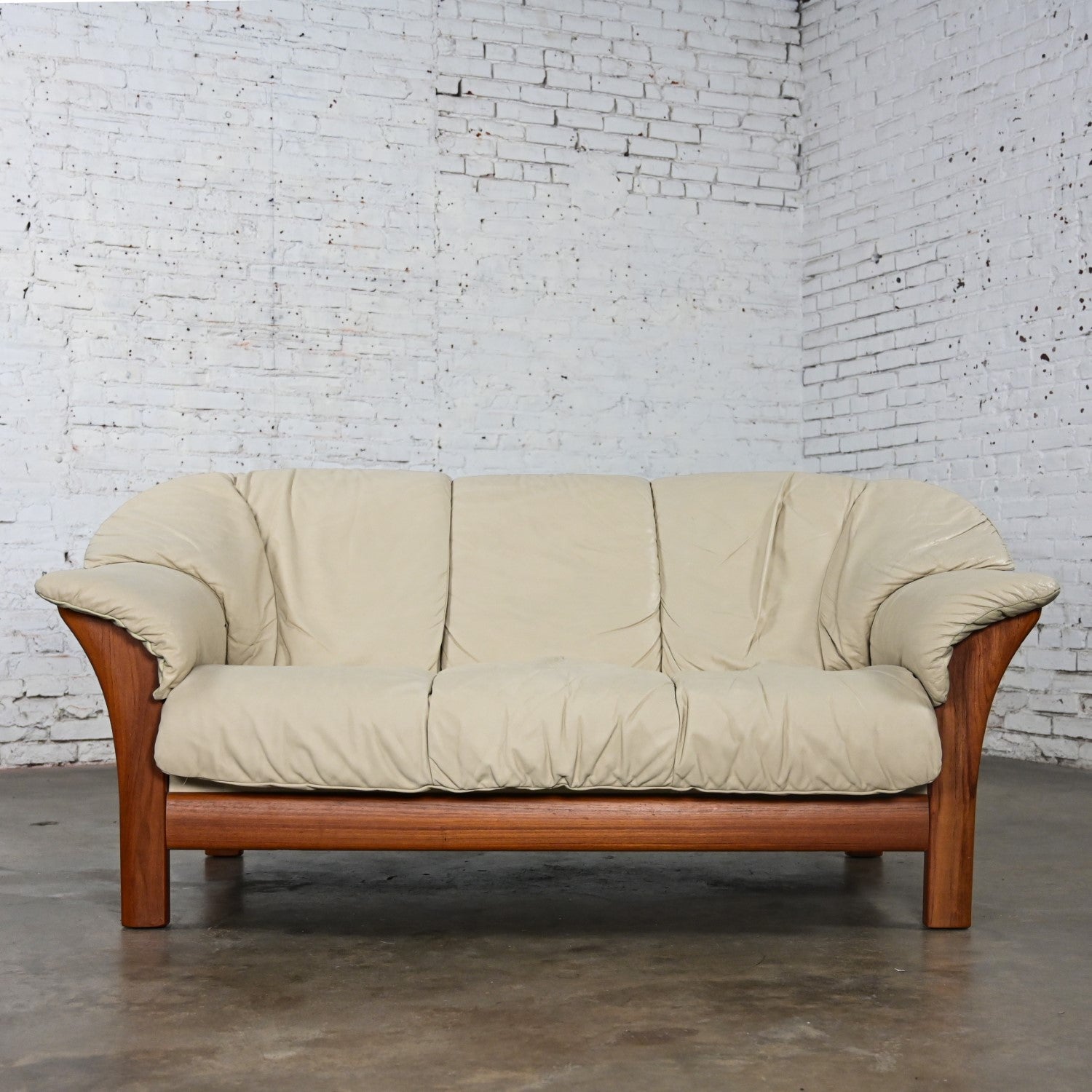 Marvelous vintage Scandinavian Modern small leather sofa Attributed to Ekornes comprised of a teak frame and off-white leather removeable seat, back, and arm zippered cushions. This piece has been attributed based upon archived research including