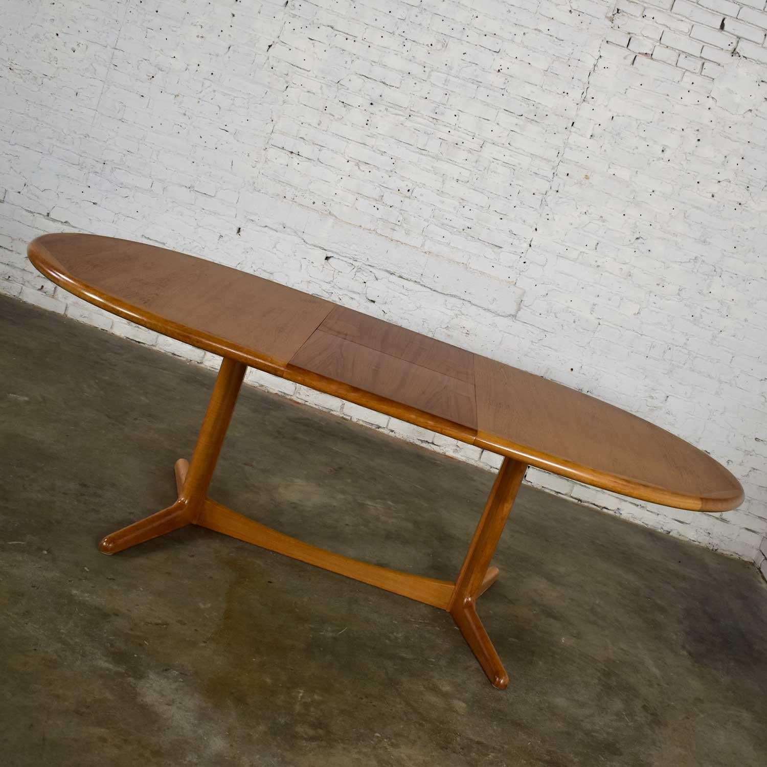 Handsome Scandinavian Modern oval expanding dining table in solid teak and teak veneer with hidden integral leaf in the style of Dyrlund. Excellent vintage condition other than there is some slight bubbling in the veneer of the leaf and on some of