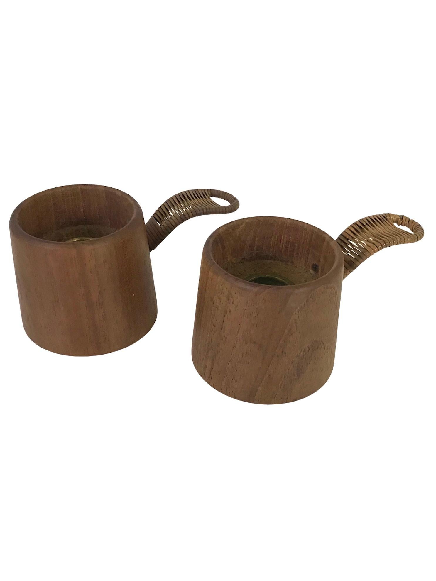 Fantastic pair of Scandinavian Mid-Century Modern Teak & Raffia 1960s candleholders. Purchased in Sweden in the 1980s. Made of solid turned teak and handle with wrapped raffia.

Measurements: 4 5/8 inches wide w. handle x 2 1/2 inches diameter top