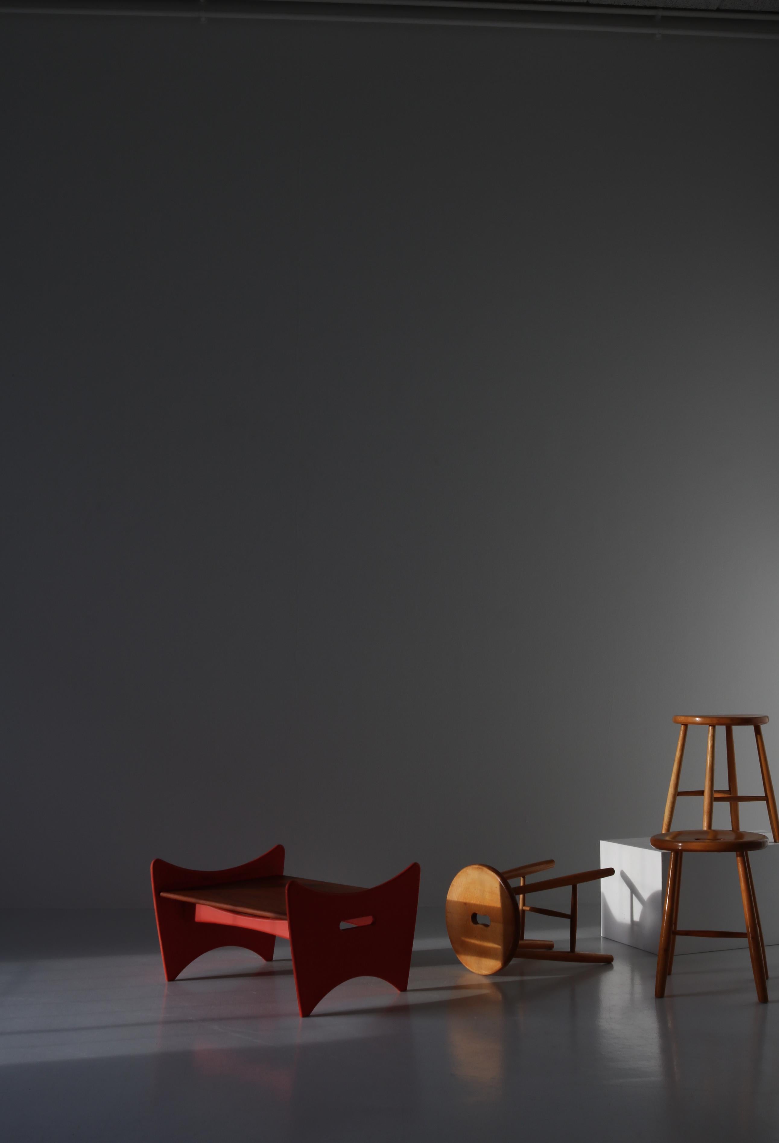 Wonderful Scandinavian Modern side table or stool by Danish architect Illum Wikkelsø. The stool is made from red lacquered wood and teakwood and features a big upholstered cushion in black leather. This piece was a part of a series of experimental
