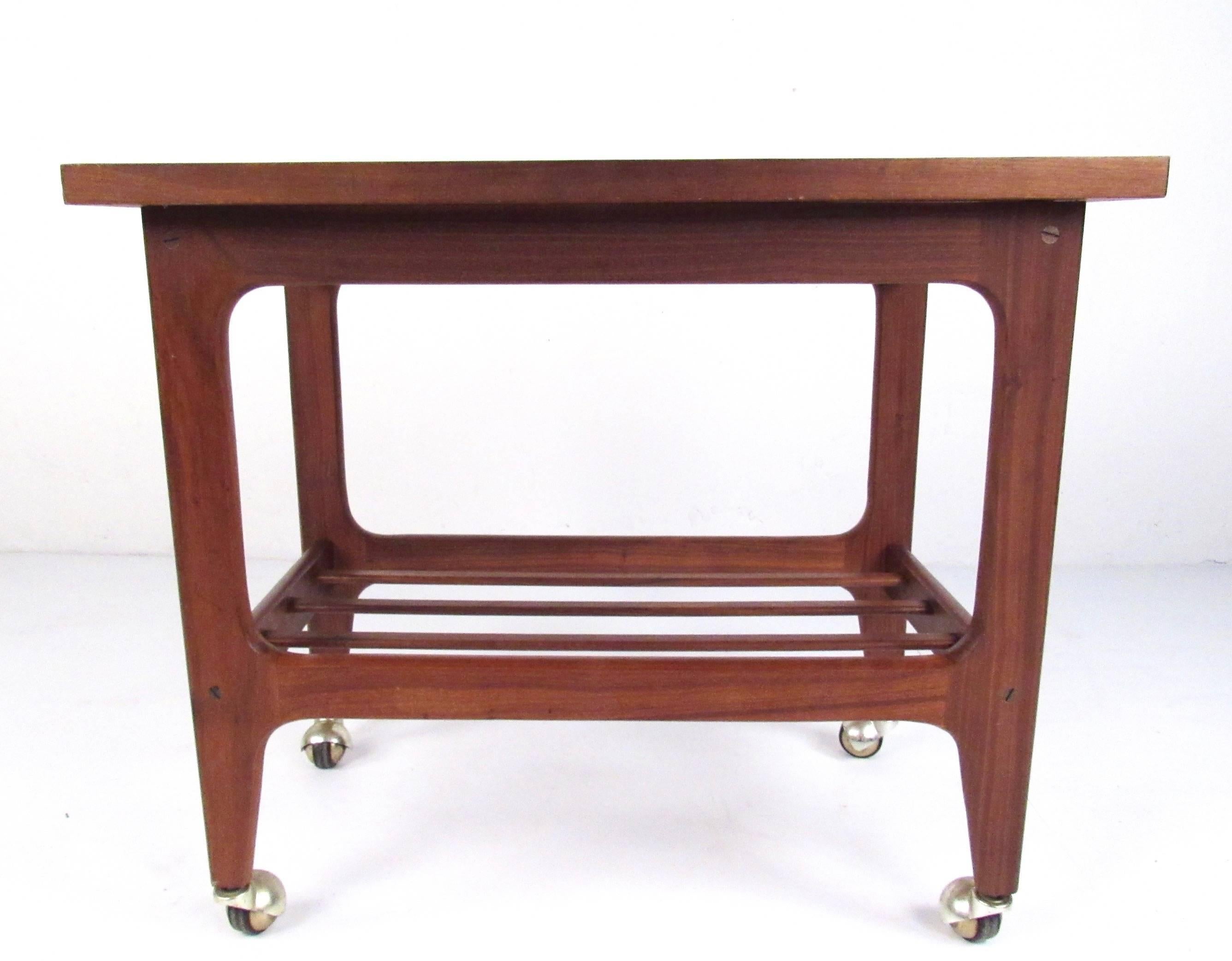 This vintage modern teak bar cart adds a splash of mid-century modern flare to any home dining or seating area. Two-tier construction and sturdy casters make this perfect for bar service or as a versatile Scandinavian Modern side table. Please