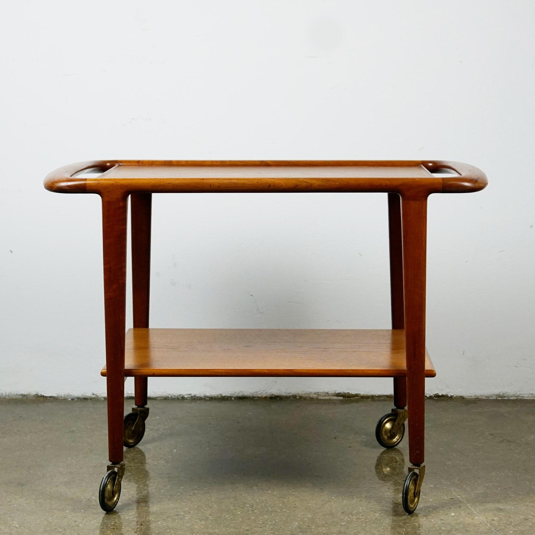This charming Scandinavian Modern teak serving table or bar cart has been designed by Niels Otto Møller, Denmark 1960s and produced by J.L. Møllers Møbelfabrik. It has beautiful organic shaped handles, the original manufacturers label and the Danish