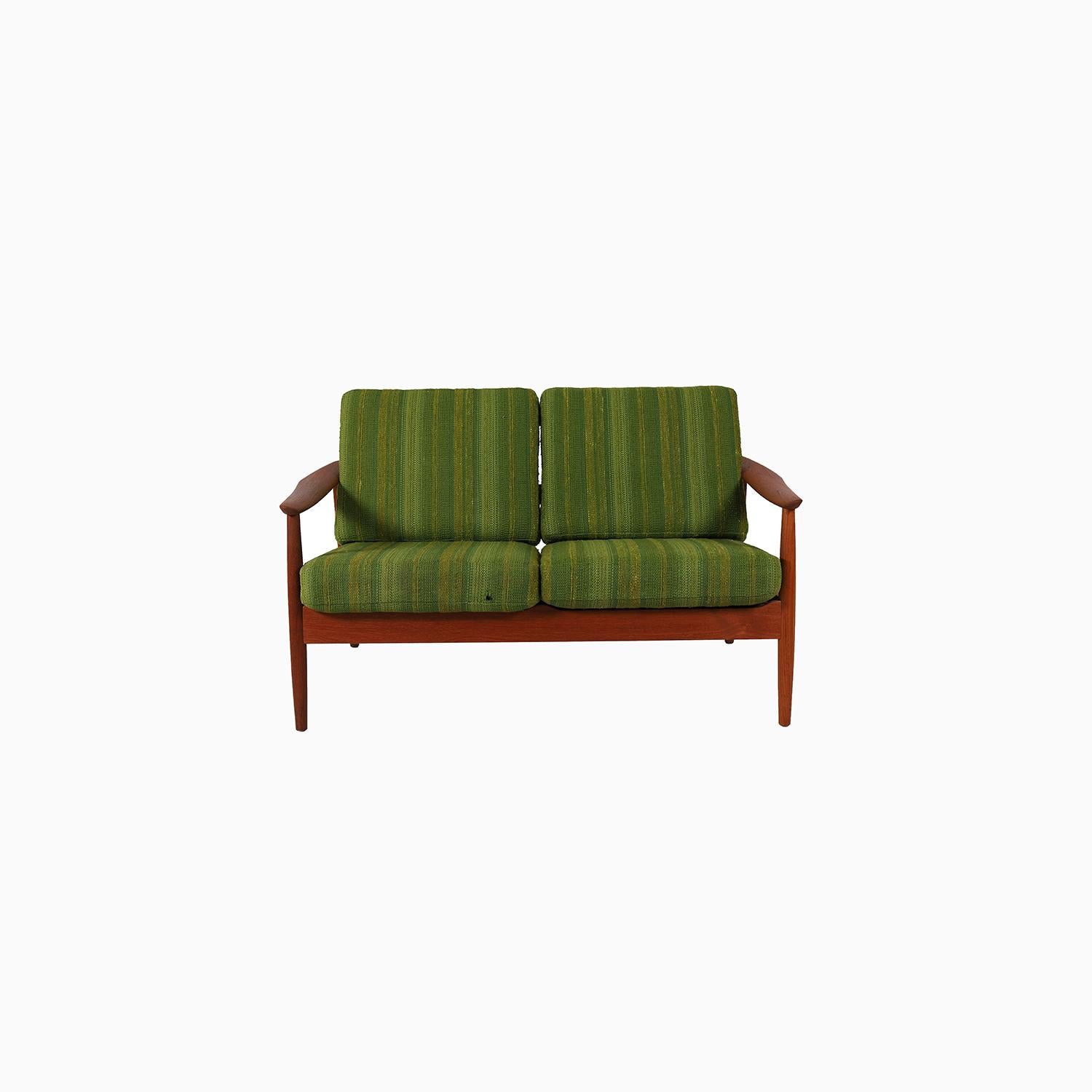 This petite settee teak settee is made from old growth teak wood finished in oil.  Cushions are a vintage textured wool with a variegated tonal stripe, in excellent functional condition.  Frame has sculptural arms that come to a point near the back