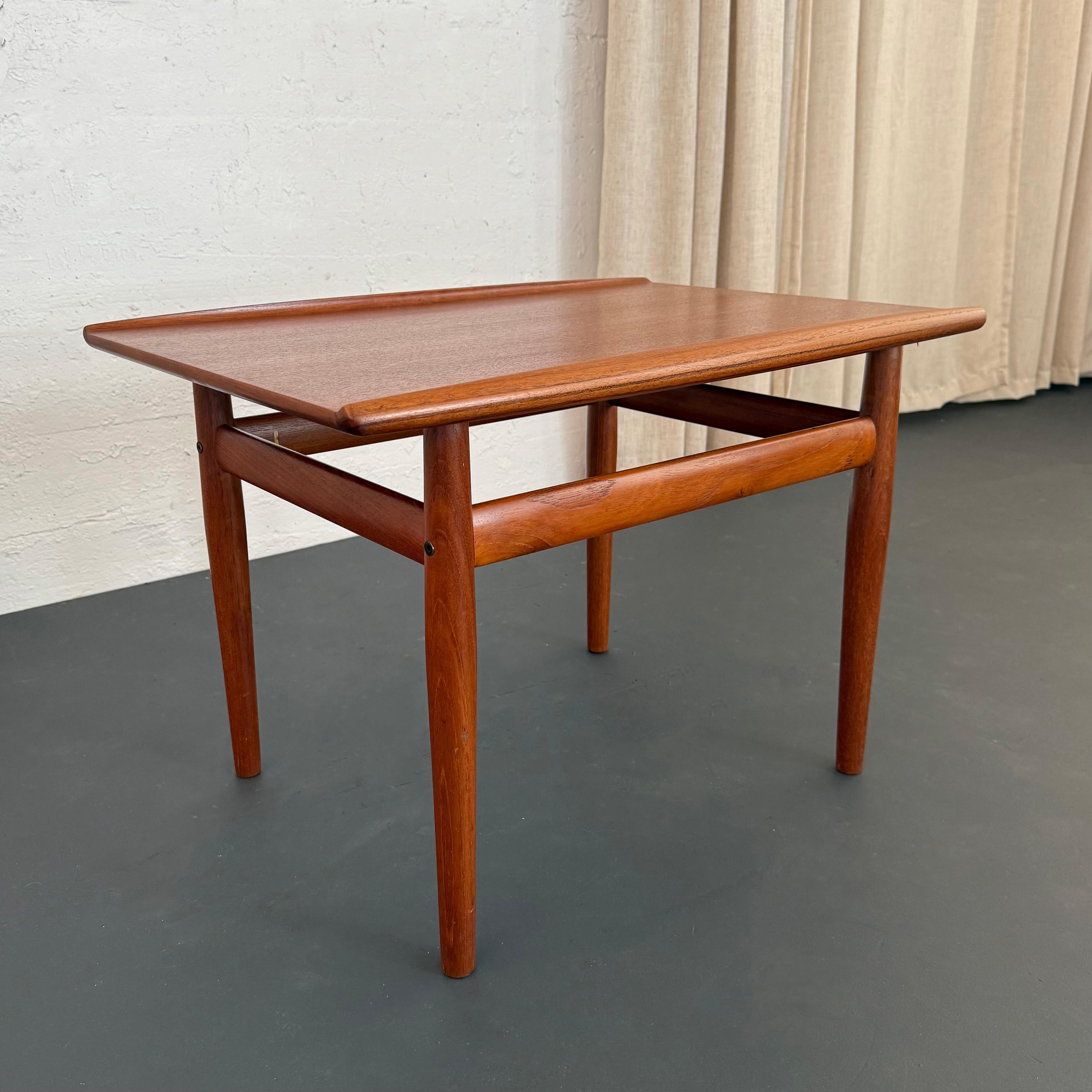Esta mesa auxiliar de teca de estilo moderno escandinavo fue diseñada por la diseñadora de muebles danesa Grete Jalk para Glostrup Møbelfabrik en la década de 1960. La mesa presenta toques sutiles pero distintivos, como los labios curvados elevados,