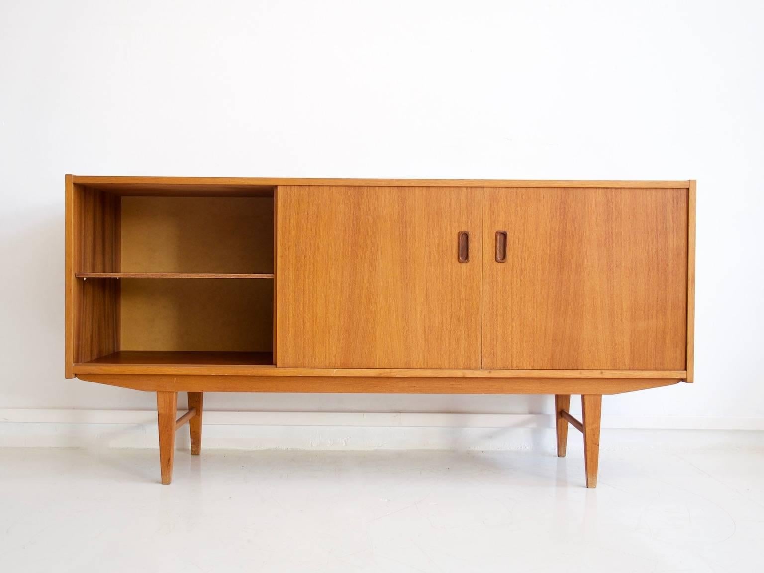Swedish sideboard veneered with teak from the 1950s-1960s. Front with five drawers and two sliding doors behind which are shelves.