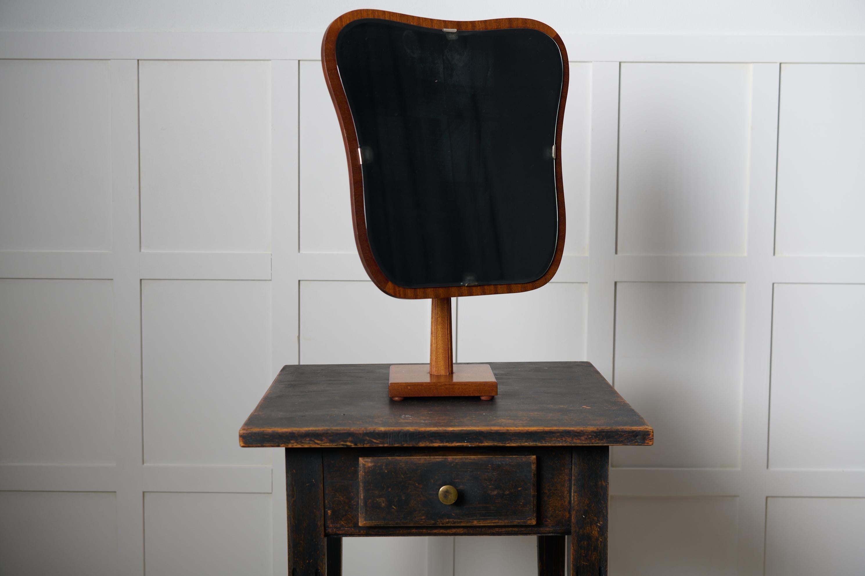 Vintage table mirror from Sweden made circa 1950s. The frame is made in teak, the base shape is approximately rectangular with organic influence as seen by the curved edges and corners. The mirror itself can be turned and tilted. Good vintage