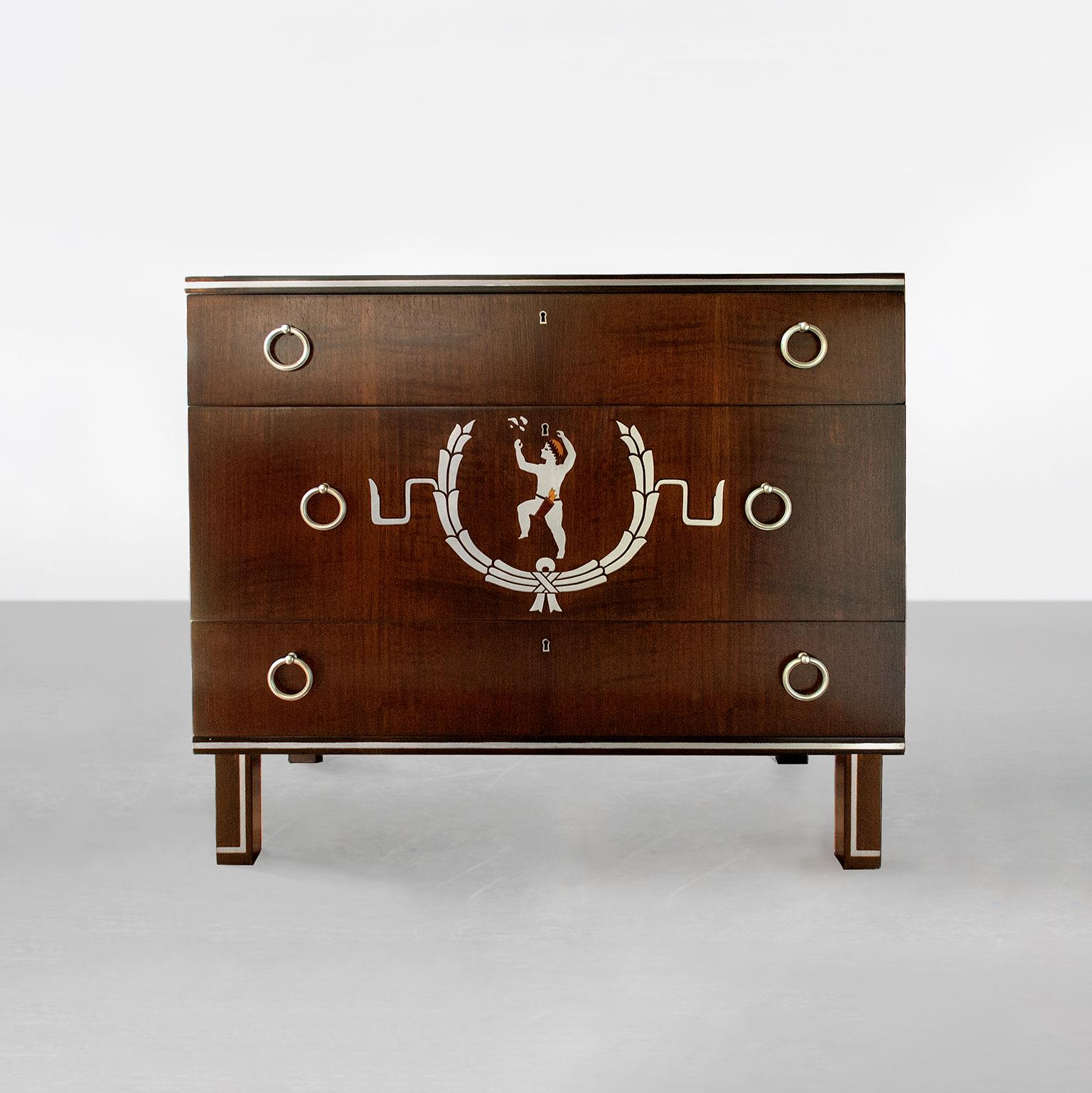 Superb Scandinavian Modern, three-drawer chest with wood marquetry and inlay in pewter. The chest's centre drawer features a young male figure wearing a laurel wreath on his head and a quiver around his waist. He is delighted by a butterfly which is