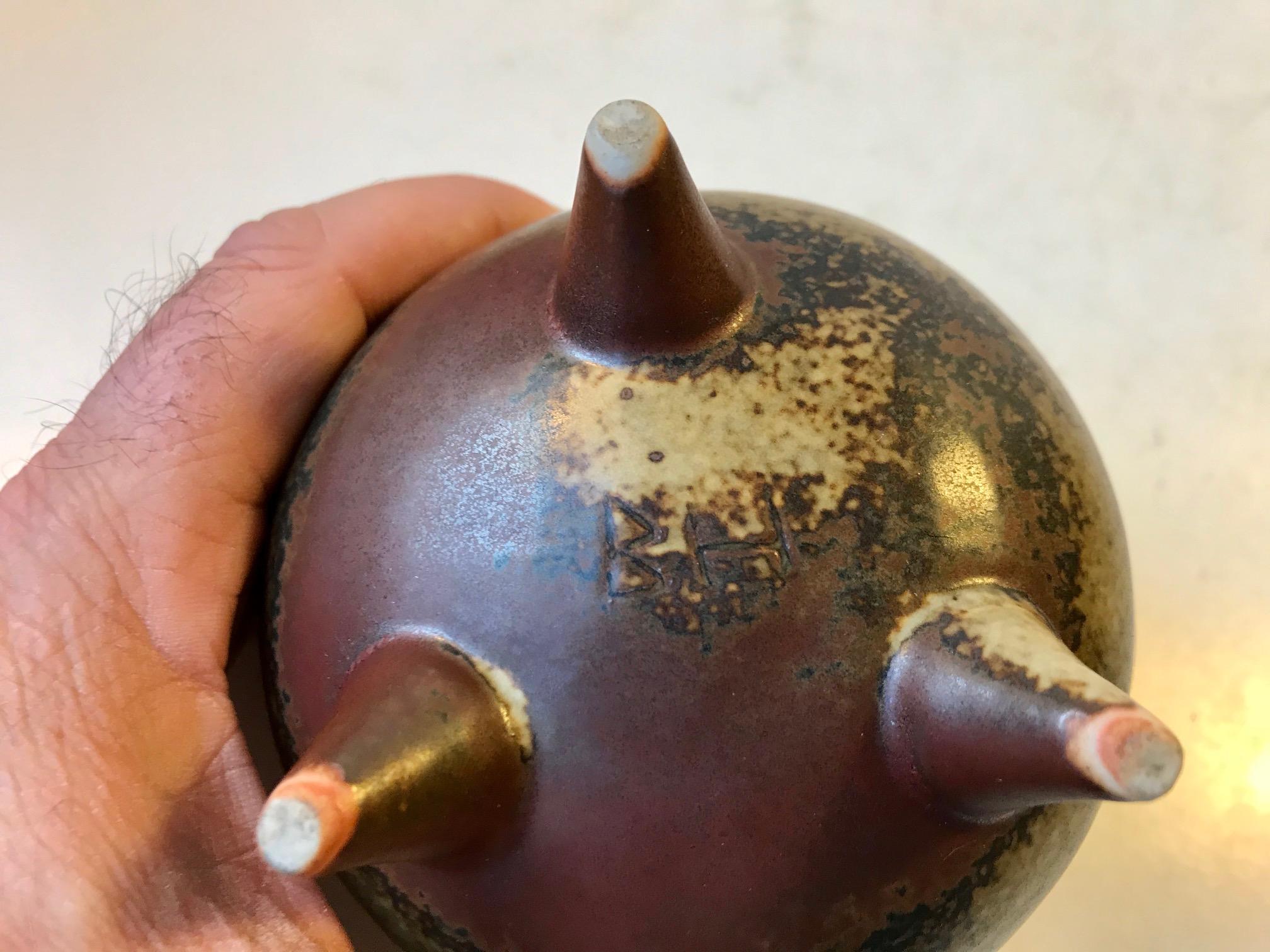 Pot shaped tristand vase in stoneware. Decorated in earthy and dusty glazes. Designed by Brita Heilimo and manufactured by Arabia in Finlands during the 1960s. The ceramist signature are imprinted beneath the base.