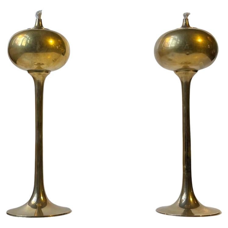 Matching pair of solid brass oil lamps. They feature onion shaped tops and trumpet shaped bases. Manufactured in Scandinavian during the 1960s or 70s in a style reminiscent of Quistgaard and Carl Cohr. Both comes with standart sized wicker.