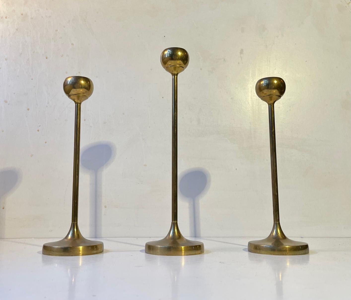 A trio of tulip shaped brass candlesticks designed and manufactured in Scandinavia during the 1960s ina style reminiscent of Pierre Forssell. The candlesticks are in a heavy quality and are to be fitted with regular sixed candles. They have not been
