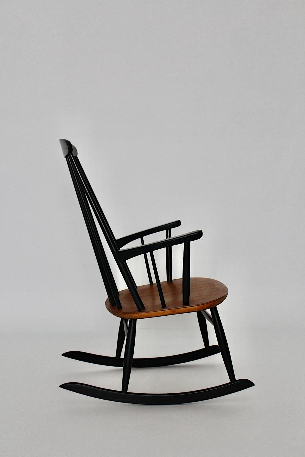 The Scandinavian Modern vintage rocking chair by Ilmari Tapiovaara for Asko 1950s, Finland.
Magnifique fauteuil à bascule en hêtre laqué noir et teck brun naturel avec accoudoirs confortables.
Idéal pour une cheminée comme chaise confortable pour