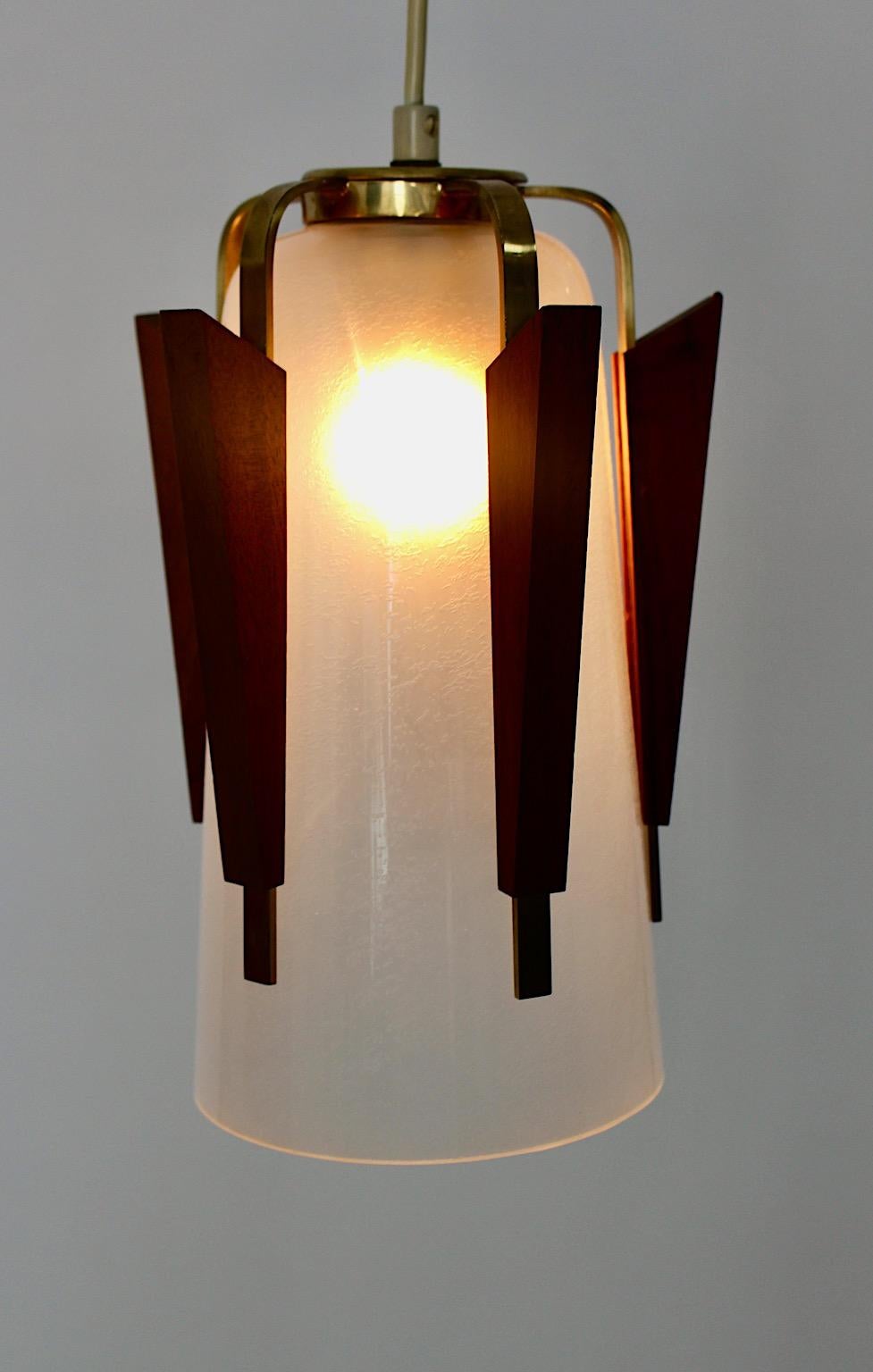 Scandinavian Modern vintage pendant or chandelier from brass, teak and frosted glass 1960s, Denmark.
A beautiful and graceful chandelier or pendant with frosted glass shade characterized through brass and teak elements.
One E 27 socket
Throughout