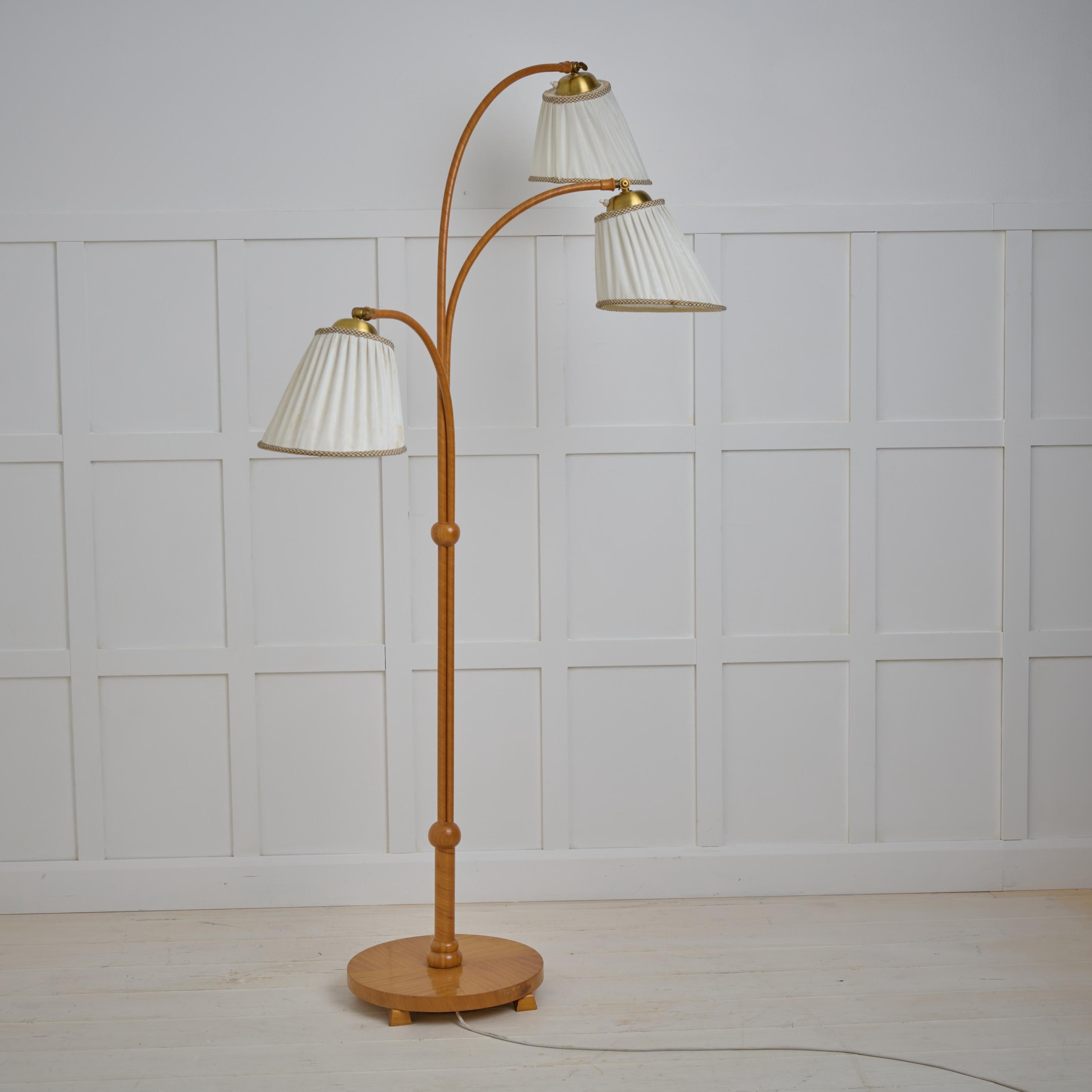 Scandinavian modern floor lamp from Sweden made during the mid 20th century, around 1940 to 1950. The base is solid elm with three light sources. The arms and shades are all adjustable. Original electrical wiring in working condition. Original lamp