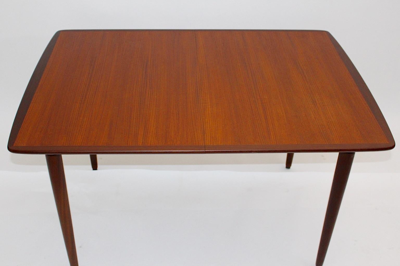 Scandinavian Modern vintage teak extending dining table or table, which shows 3 extending leaves.
Each of the leaves has the dimensions 30 cm x 90 cm.
The table plate contrasts with a dark stained border.
The vintage condition of the vintage teak