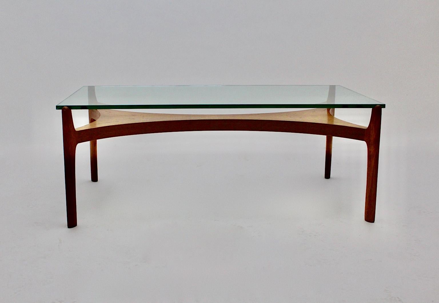 A Scandinavian Modern vintage coffee table designed by Sven Ellekaer 1960s, which was made of solid teak and veneered teak. The sculptural teak base is topped with an original clear glass plate with a thickness of 15 mm.
The vintage condition of