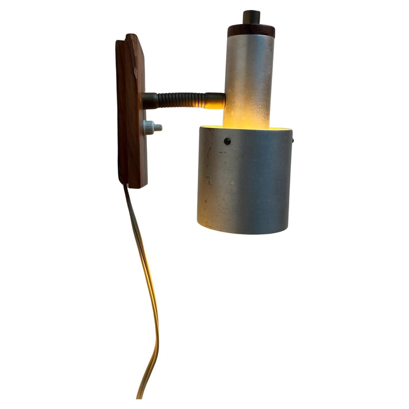 Small adjustable wall lamp made aluminium and teak. It features an adjustable brass goose-neck and on/of switch to its base. It was made in Denmark during the 1960s probably by Lyfa in style reminiscent of Jo Hammerborg - Fog & Mørup. Measurements: