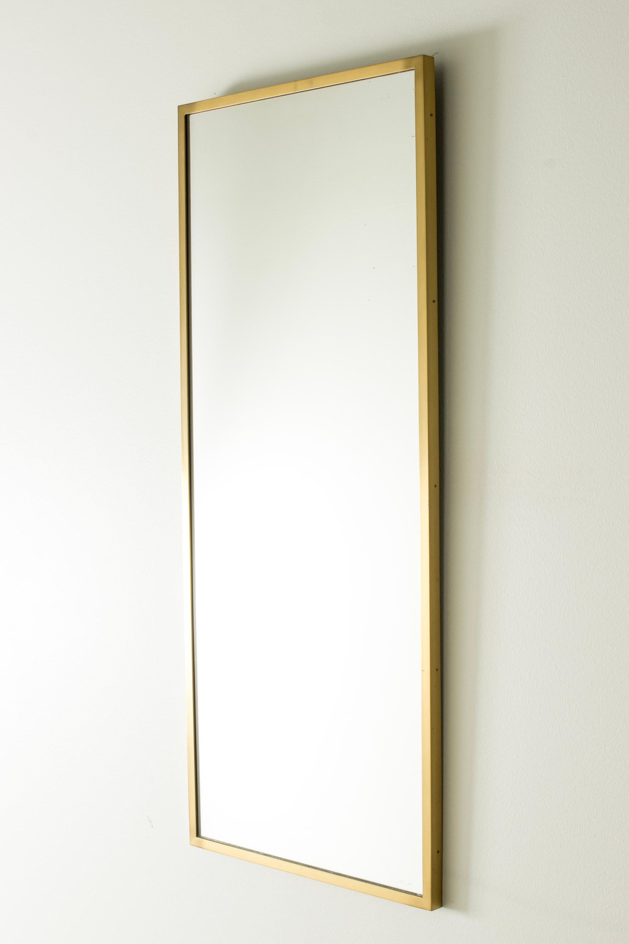 Elegant miroir mural de Hans-Agne Jakobsson au design épuré et rectangulaire. Cadre en laiton brossé.