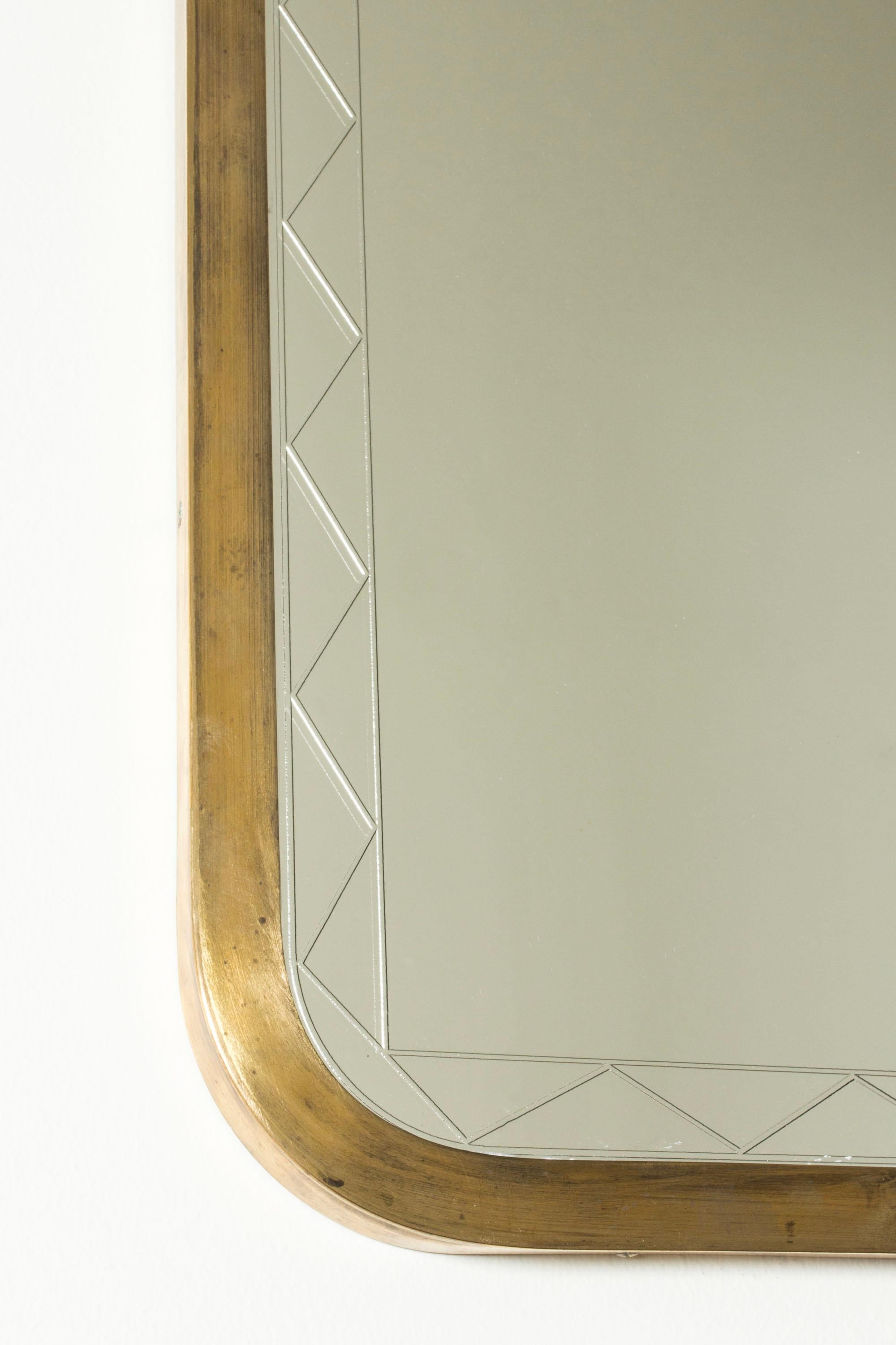 Lovely Swedish Modern wall mirror, with a brushed brass frame. Etched graphic pattern on the glass inside the edge of the frame.