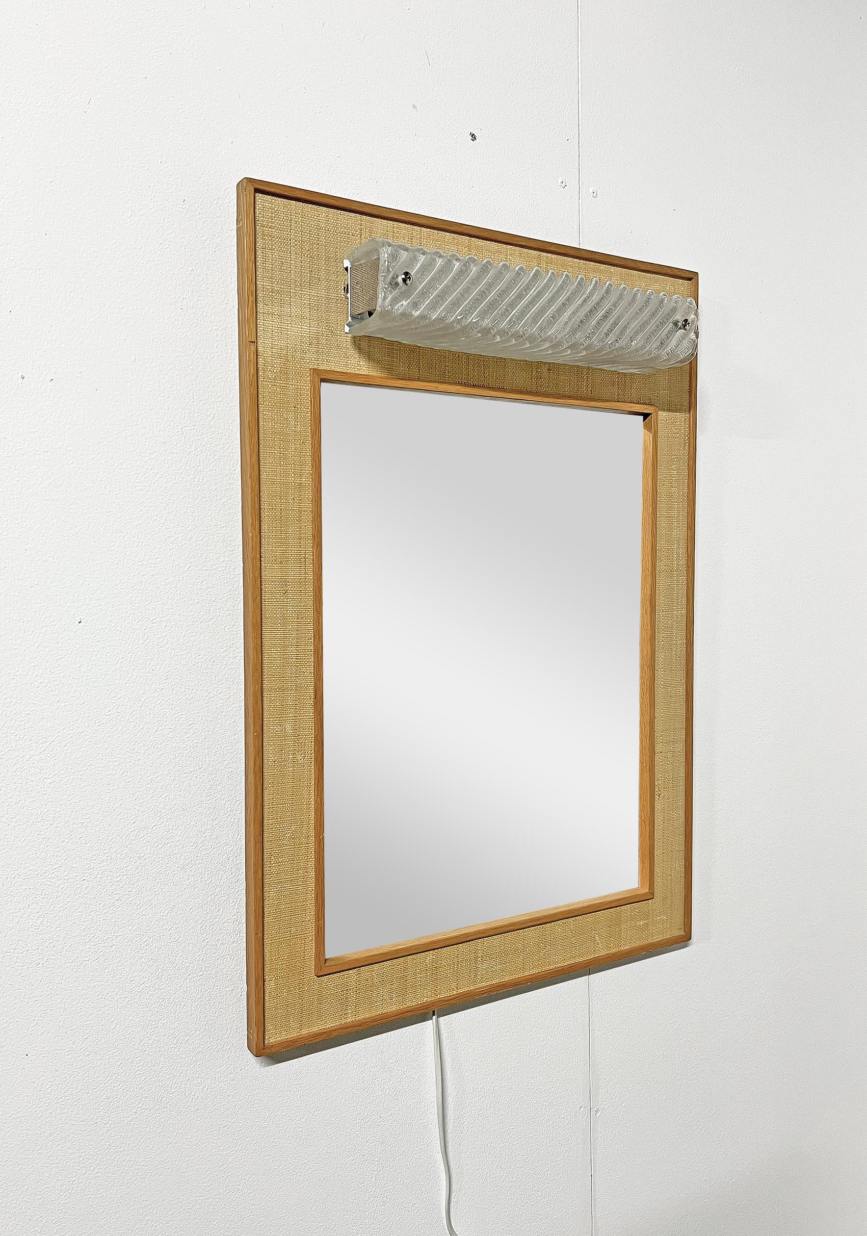 Scandinavian Modern wall mirror with lighting, Fröseke AB Nybrofabriken,  ca 1950's. 
Signed with makers mark.
Good vintage condition, wear and patina consistent with age and use. 
Wear and patina on rattan and oak. Scratches.