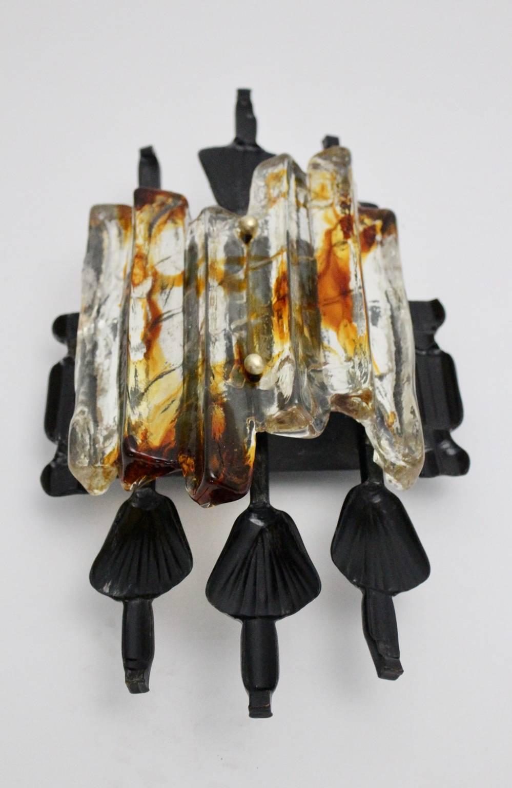 A Scandinavian modern indoor and outdoor vintage wall sconce by Tom Ahlström, circa 1970, which was manufactured by A & E Lights Sweden.
The wall sconce has a heavy black lacquered iron frame and a clear and amber colored glass part.
The vintage