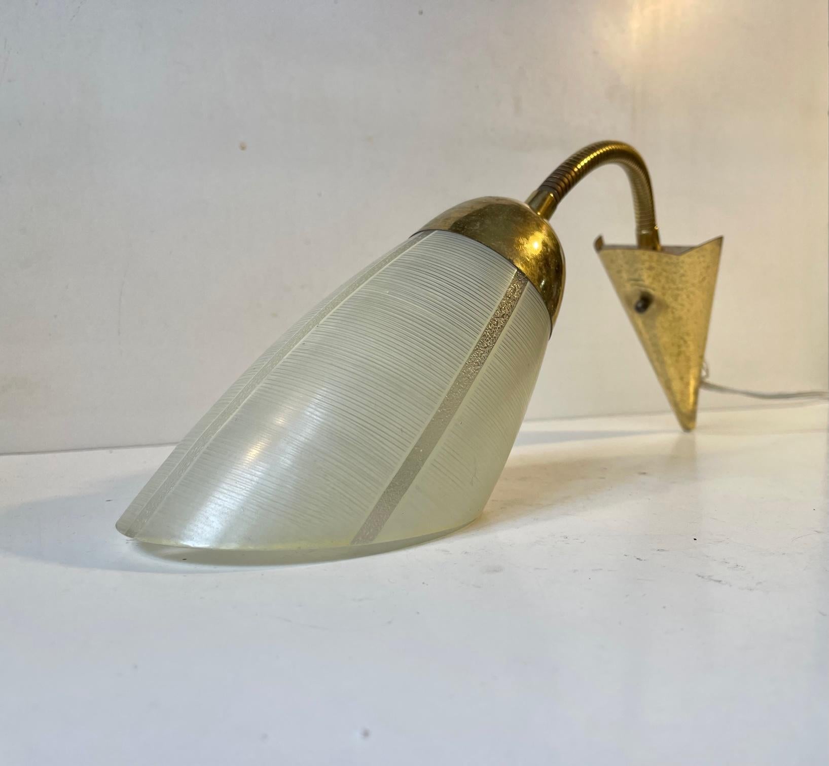 Early 1950s wall light made in Scandinavia in a style reminiscent of Stilnovo and the french modernist movement. Its composed of patinated brass and mounted with an angle-cut pastel white glass shade. with intricate horizontal stripes. Its