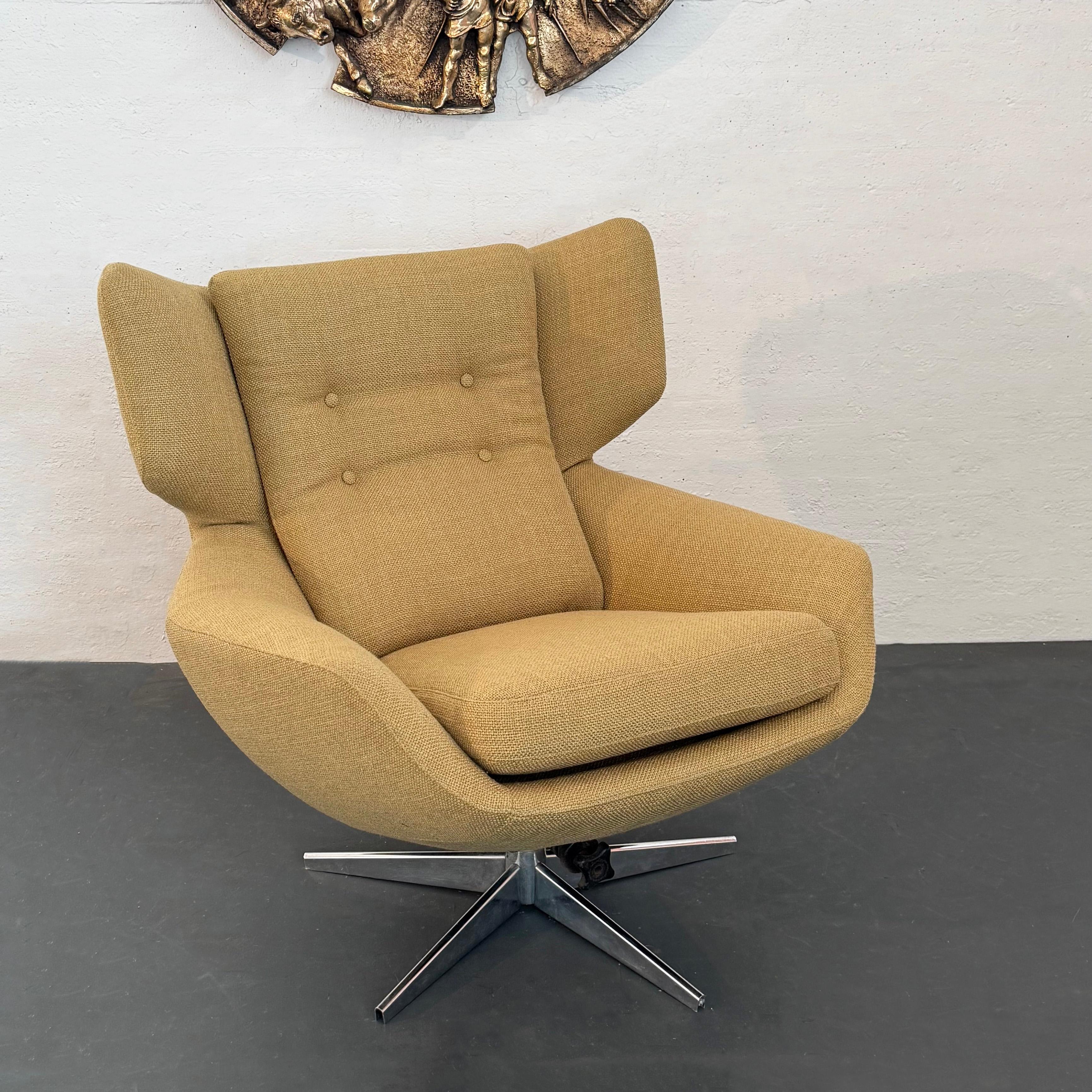 Esta tumbona con respaldo escandinavo moderno se fabricó a mediados del siglo XX en Suecia. La silla, totalmente tapizada, tiene una generosa forma de huevo con respaldo alado que gira sobre una base cromada de 4 puntas cuya inclinación es