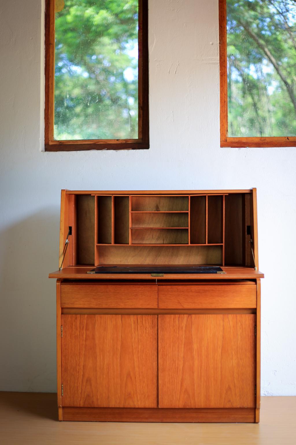 A midcentury teak escritoire or writing bureau by Remploy in the clever, space saving Scandinavian modern style. It has a drop front desk with pigeon hole unit, two drawers, and a two door cabinet below. 

It has the original key and the maker's