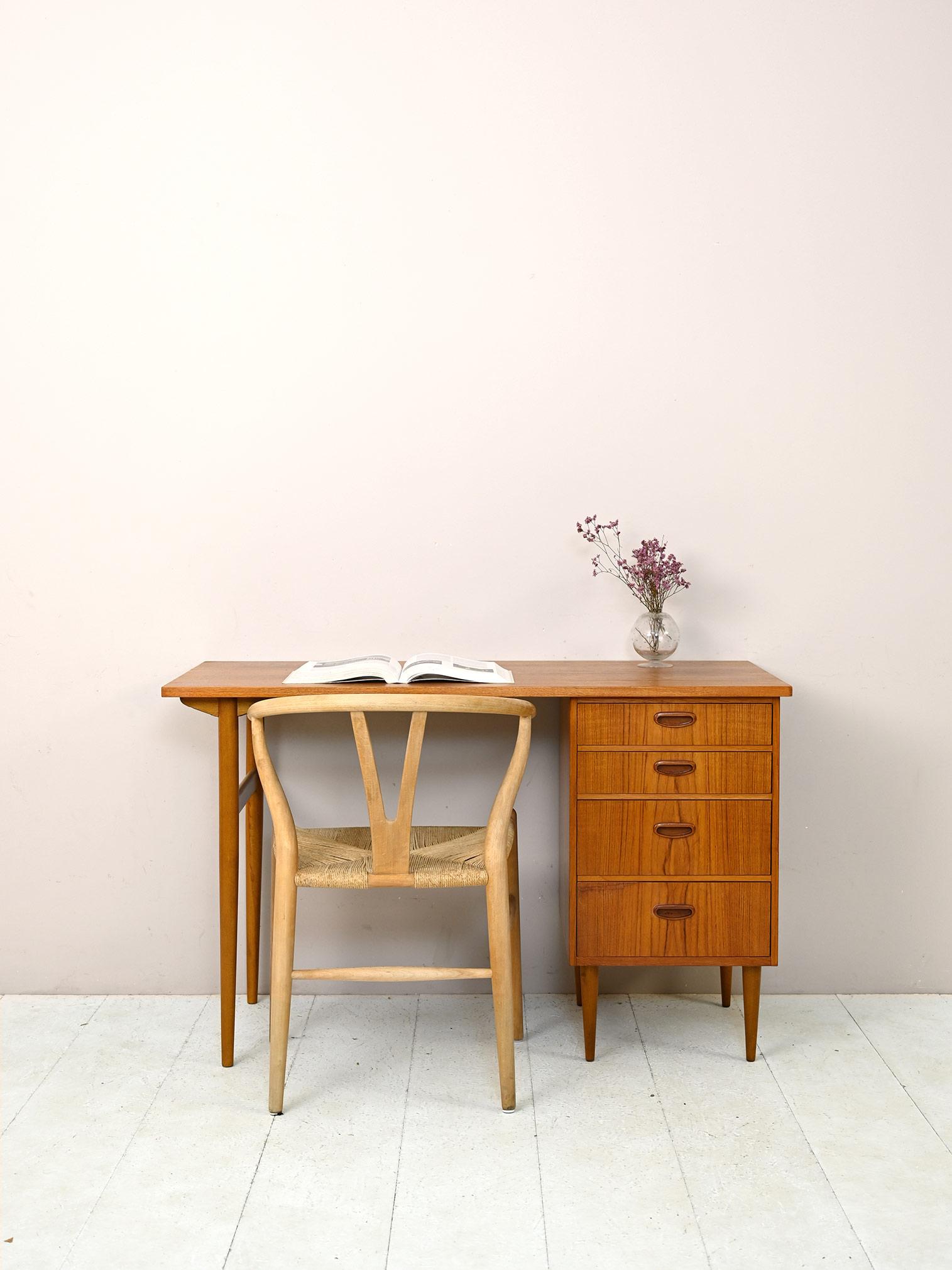 Swedish vintage desk.

A work table whose top rests on the 4 drawers on one side and long tapered legs on the other.
The carved wooden drawer handles and pronounced wood grain give it a unique and elegant look.
Try placing it in your bedroom to