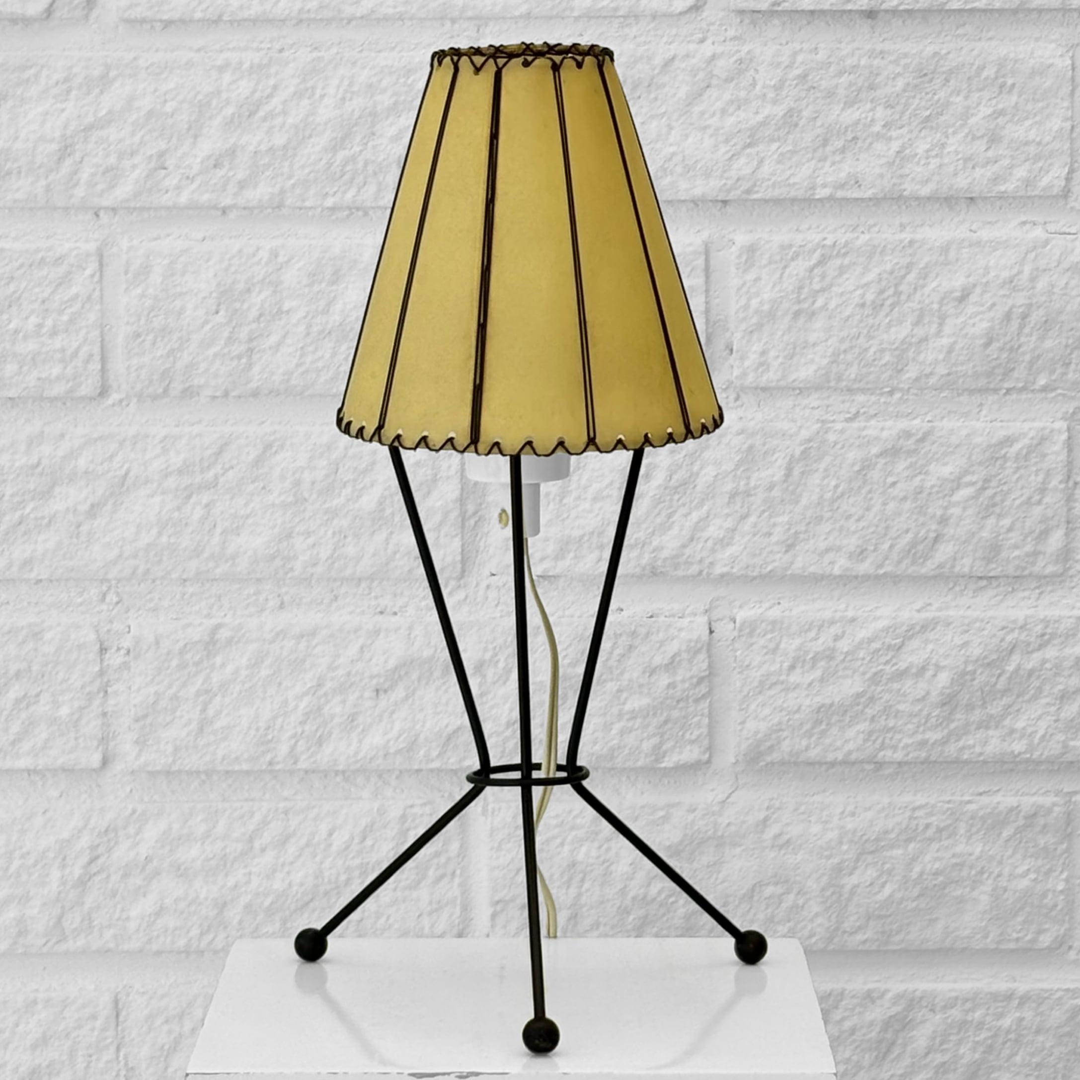 Una lámpara de mesa de la Era Atómica, modelo B10, producida por el fabricante sueco LECO Armatur AB en Gotemburgo durante la década de 1950. La pequeña lámpara tiene un escultural trípode de metal pintado de negro, que se apoya en tres patas en