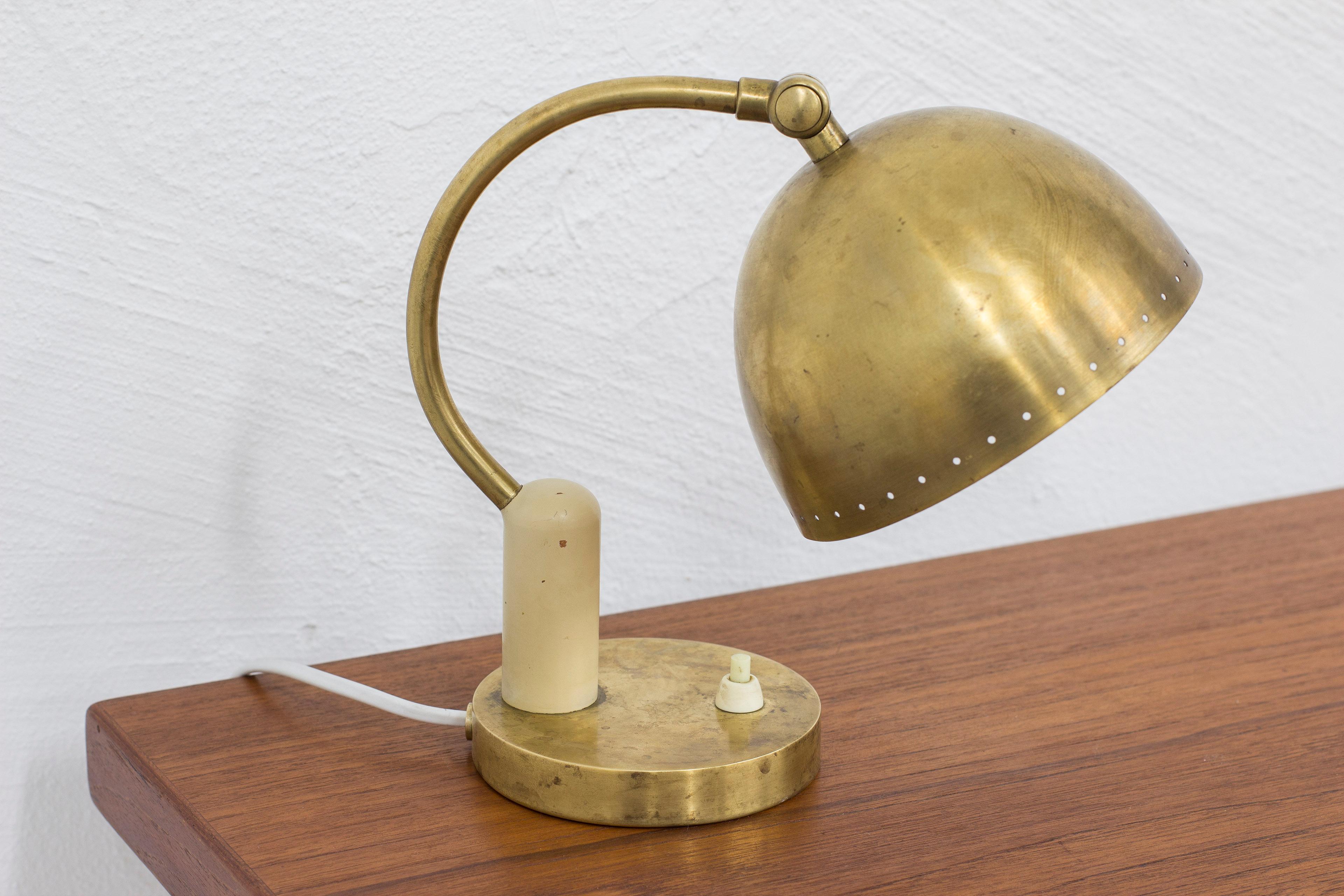 Table or wall lamp attributed to Nordiska Kompaniet, NK. Produced in Sweden during the 1930s. Made from brass and bone colored metal. Adjustable in angle. Light switch  on the base in working order. The lamp can also be hung as a wall lamp. Good