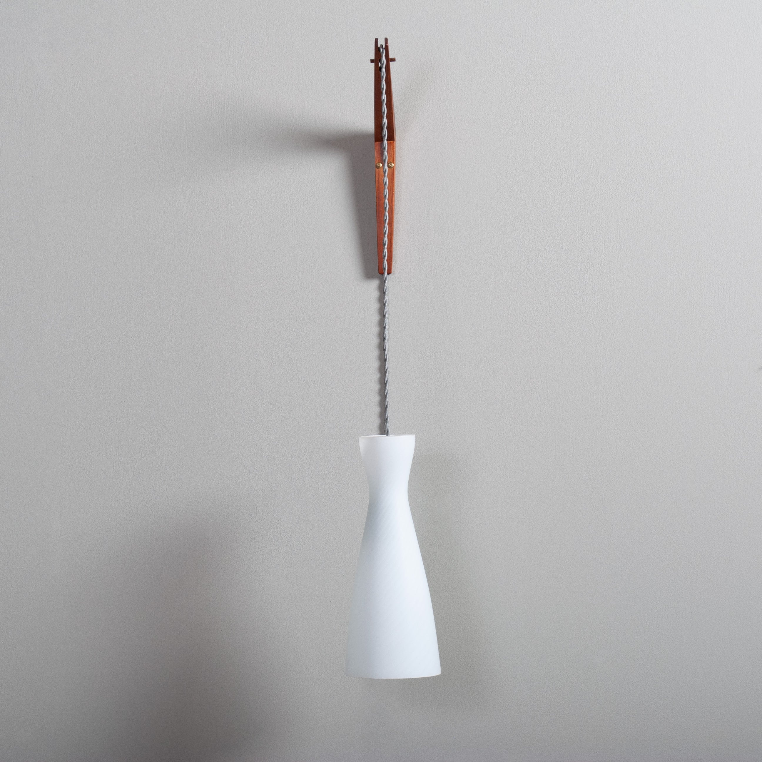 This Modernist wall lamp can be either hardwired into an existing wall circuit or cable with inline switch to plug. Whichever, its a very slick design. Produced in Denmark circa 1960 and made from teak and glass. 
The cable winds through the teak
