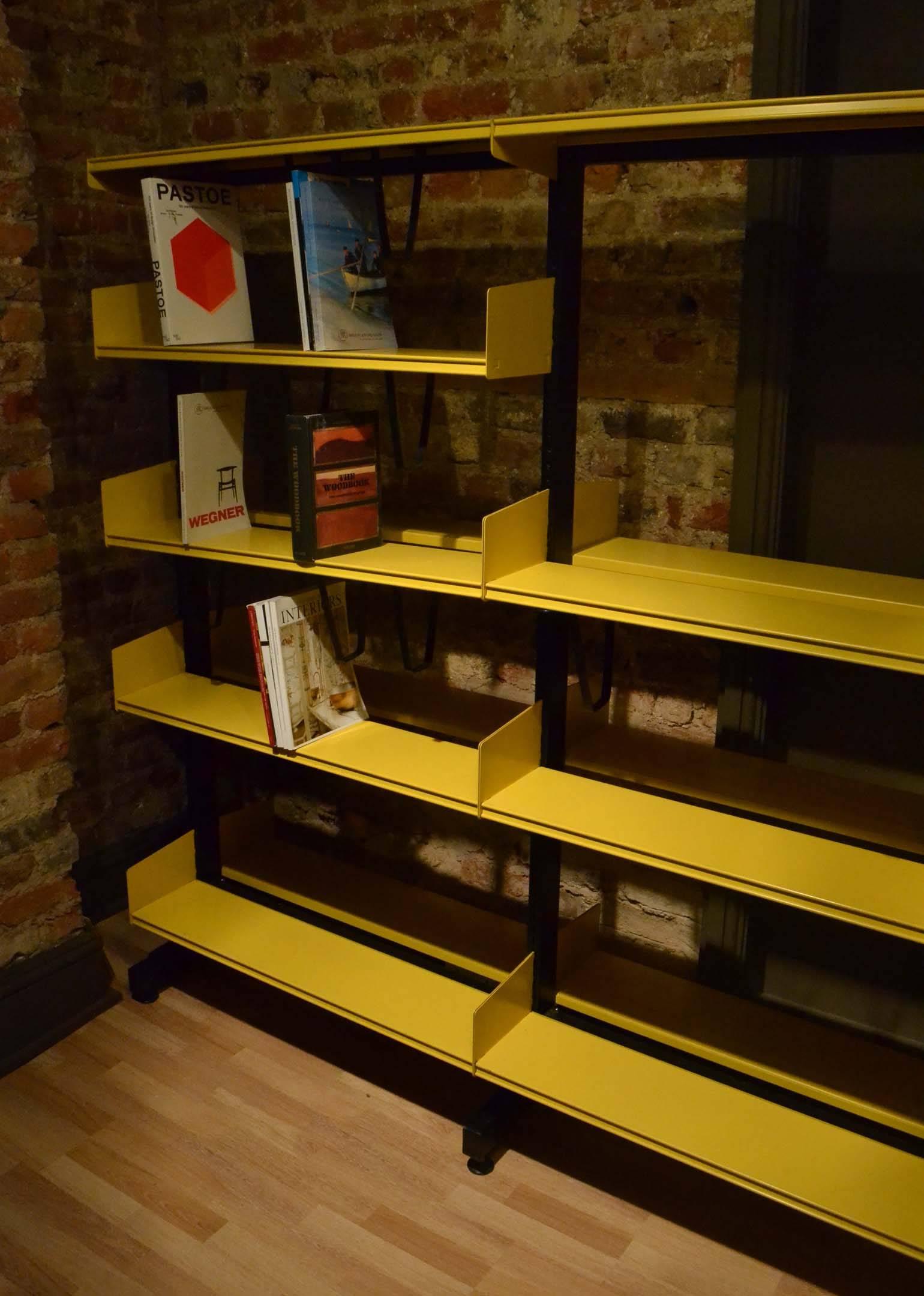 Vintage metal Reska library shelving was developed in 1949 by Rudolph Koreska in Denmark. Free standing black metal cantilever structure with mustard yellow metal double-sided book shelves. The system can be used as a room divider as well as