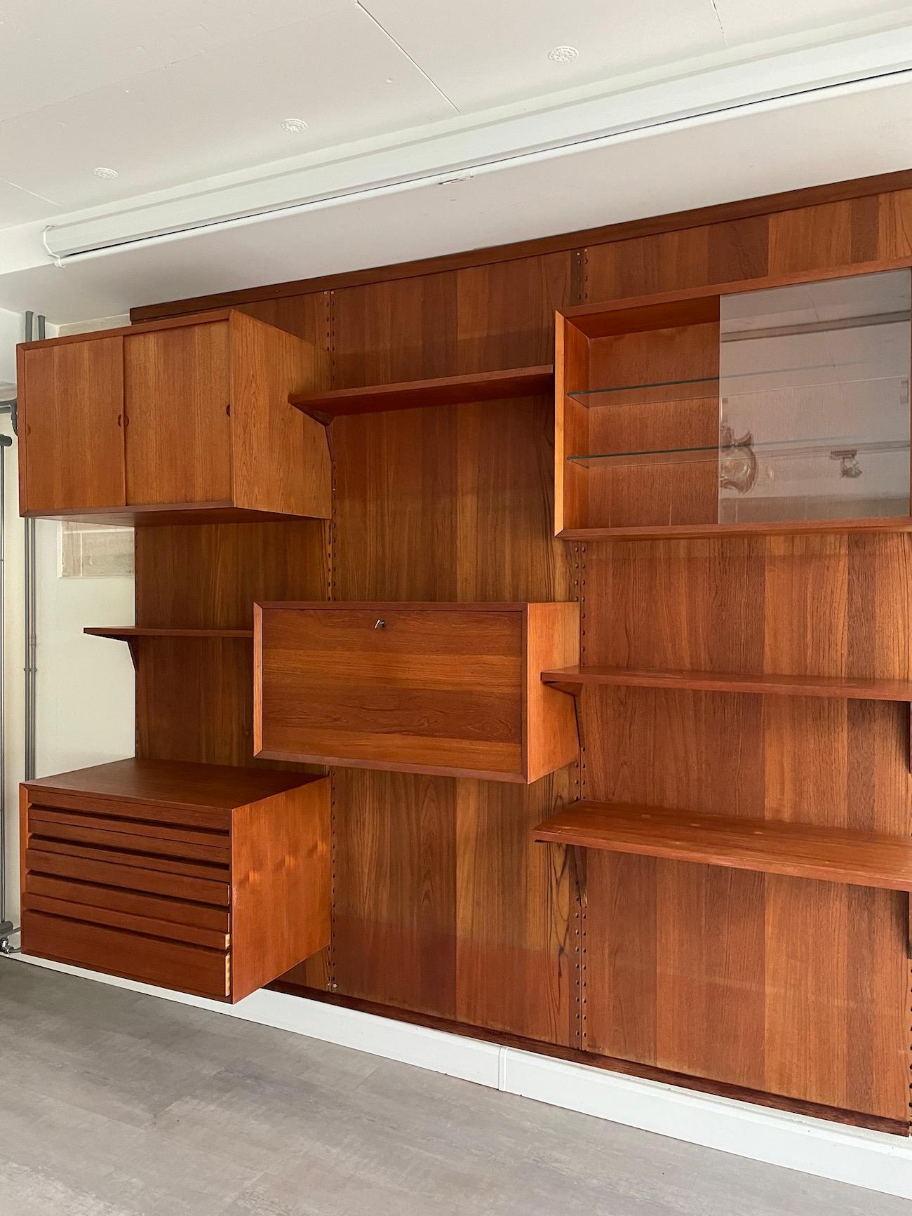 Scandinavian shelf by Poul Cadovius (Denmark, 1911-2011). Teak version with three wall panels supporting several shelves and boxes.

 This wall system is composed of :
- 4 shelves 
- 1 box with sliding doors in wood
- 1 glass sliding door