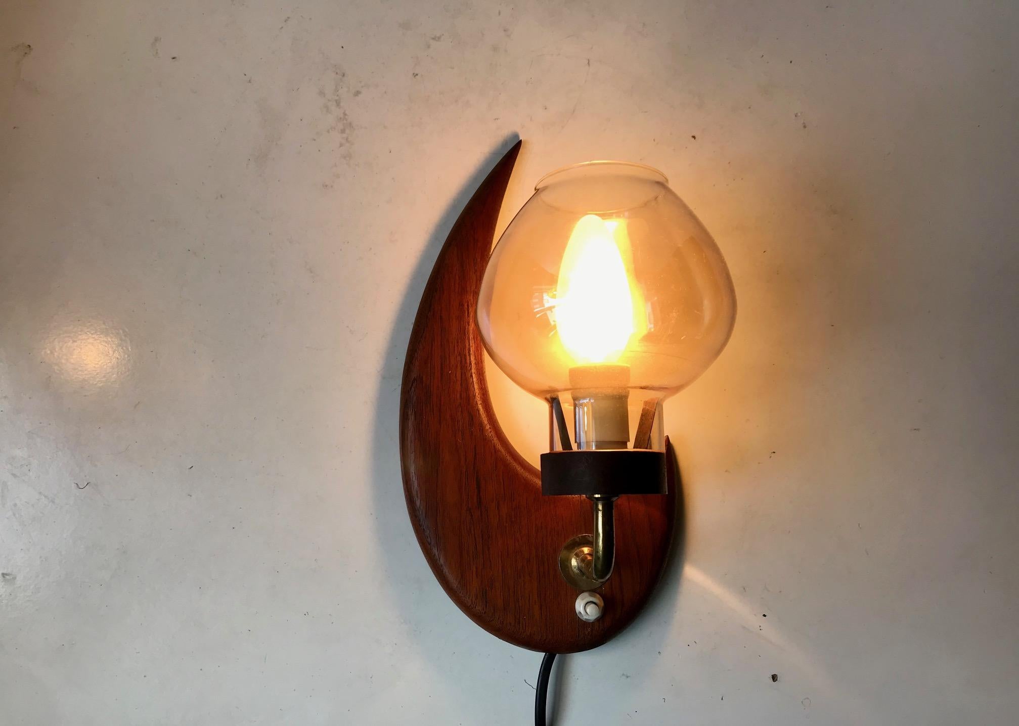 Moon shaped fixed wall light composed of solid teak, brass and smoke glass. Made from excess furniture wood during the early 1960s by an anonymous Scandinavian maker. Please notice that it has a hairline crack repair. Barely visible to the bottom of