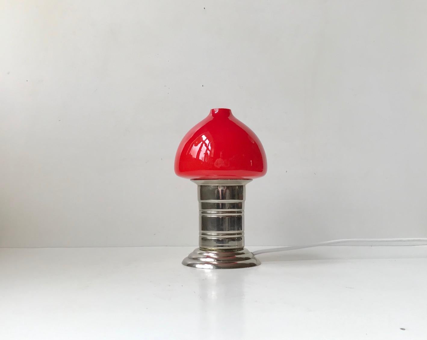 Unusual and petite table light executed in nickel plated steel and featuring a mushroom shade in cased red glass that turn orange when lid. Unknown Scandinavian maker/design, circa 1960-70. Measurements: H: 20 cm, D: 12 cm.
