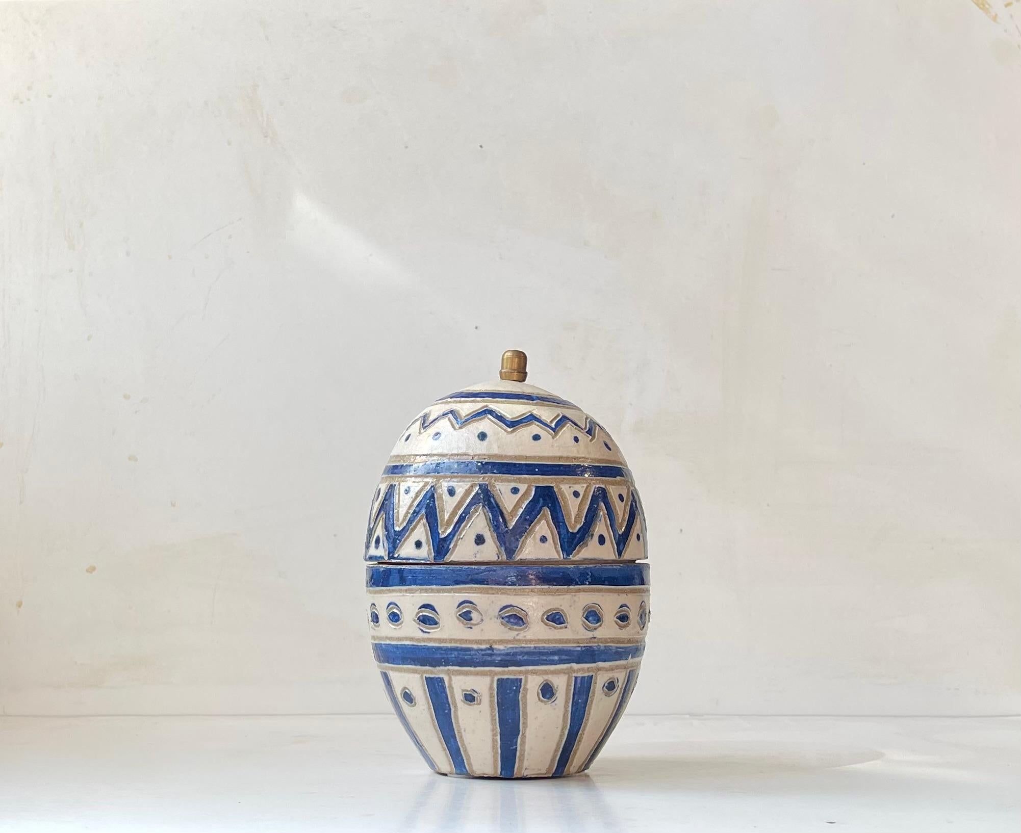 Large ovoid lidded jar - egg trinket glazed and decorated naively with geometric pattern. Practical brass knob placed at the lids top. Signed VJ - un-identified Scandinavian ceramist circa 1970-75. 
Measurements: H: 20 cm, Diameter: 13 cm.