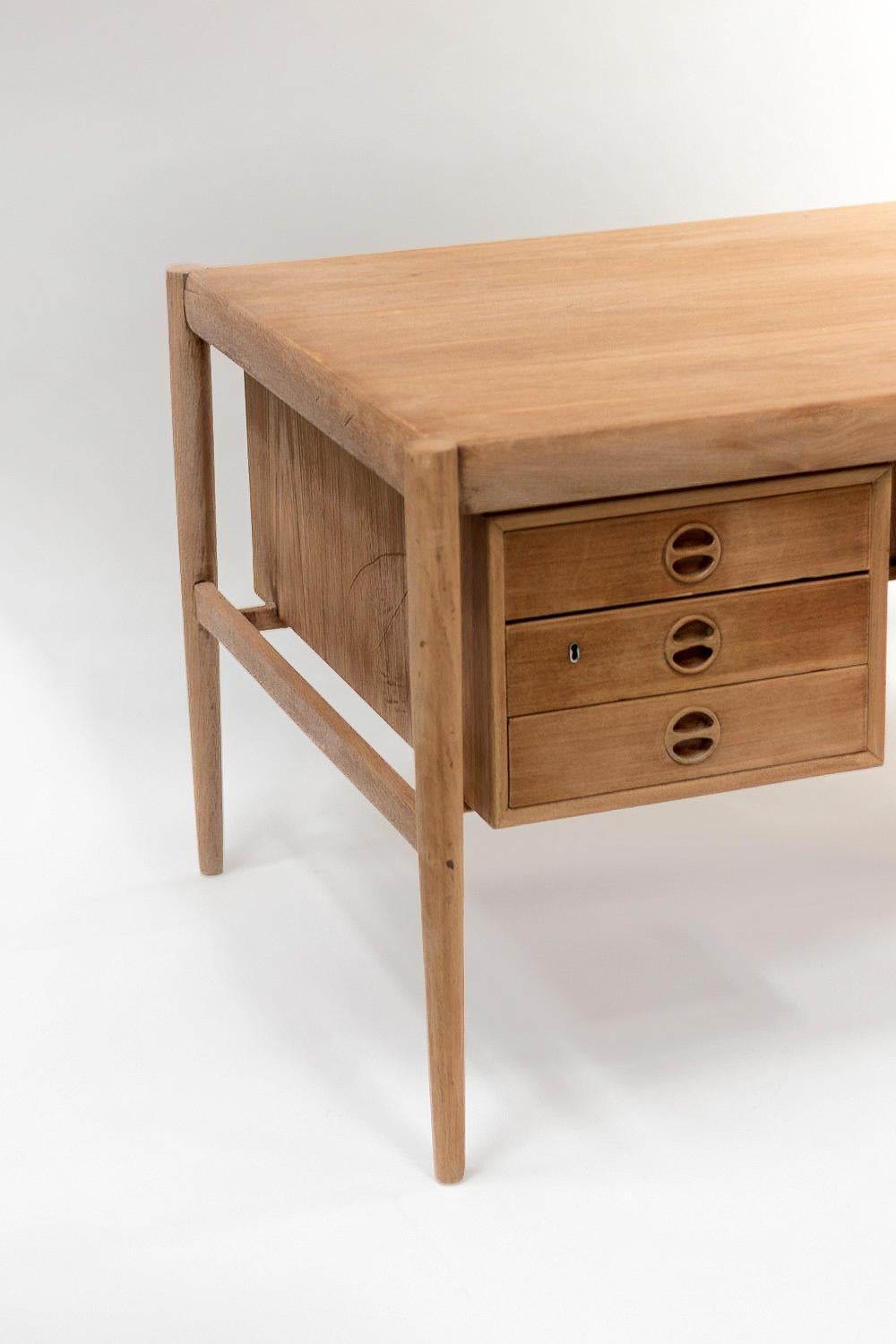 Scandinavian natural teak desk made of two boxes with three drawers each. Rectangular top standing on four cylindrical legs: uprights detached from the boxes under the tray. Circular handles inside drawer’s facade.

Scandinavian work realized
