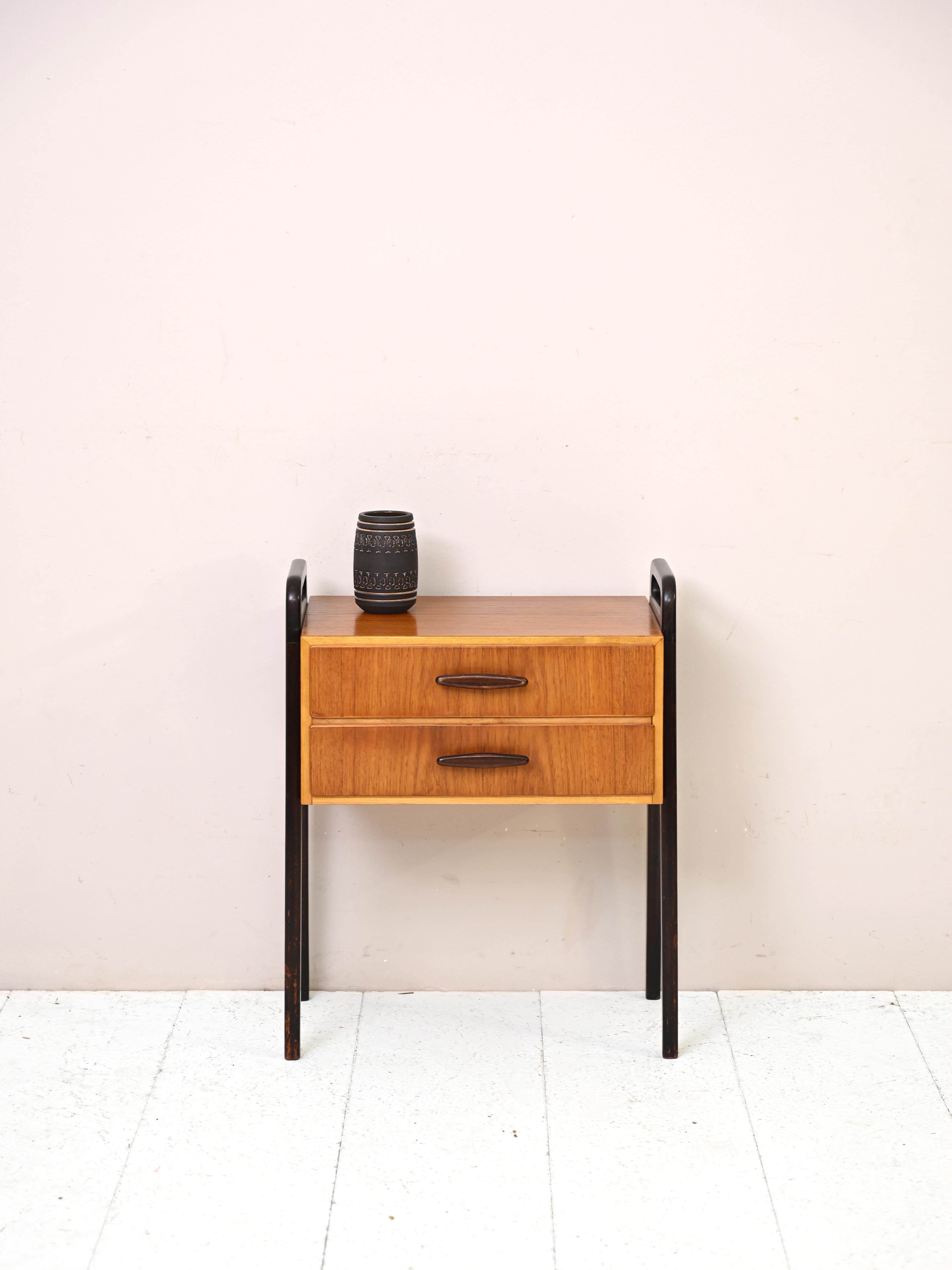Original vintage teak cabinet with drawers.

This piece of furniture from the 1960s features a simple square teak wood frame with wooden handle drawers. Its uniqueness lies in the black-painted wooden U-shaped frame that goes into the legs and and