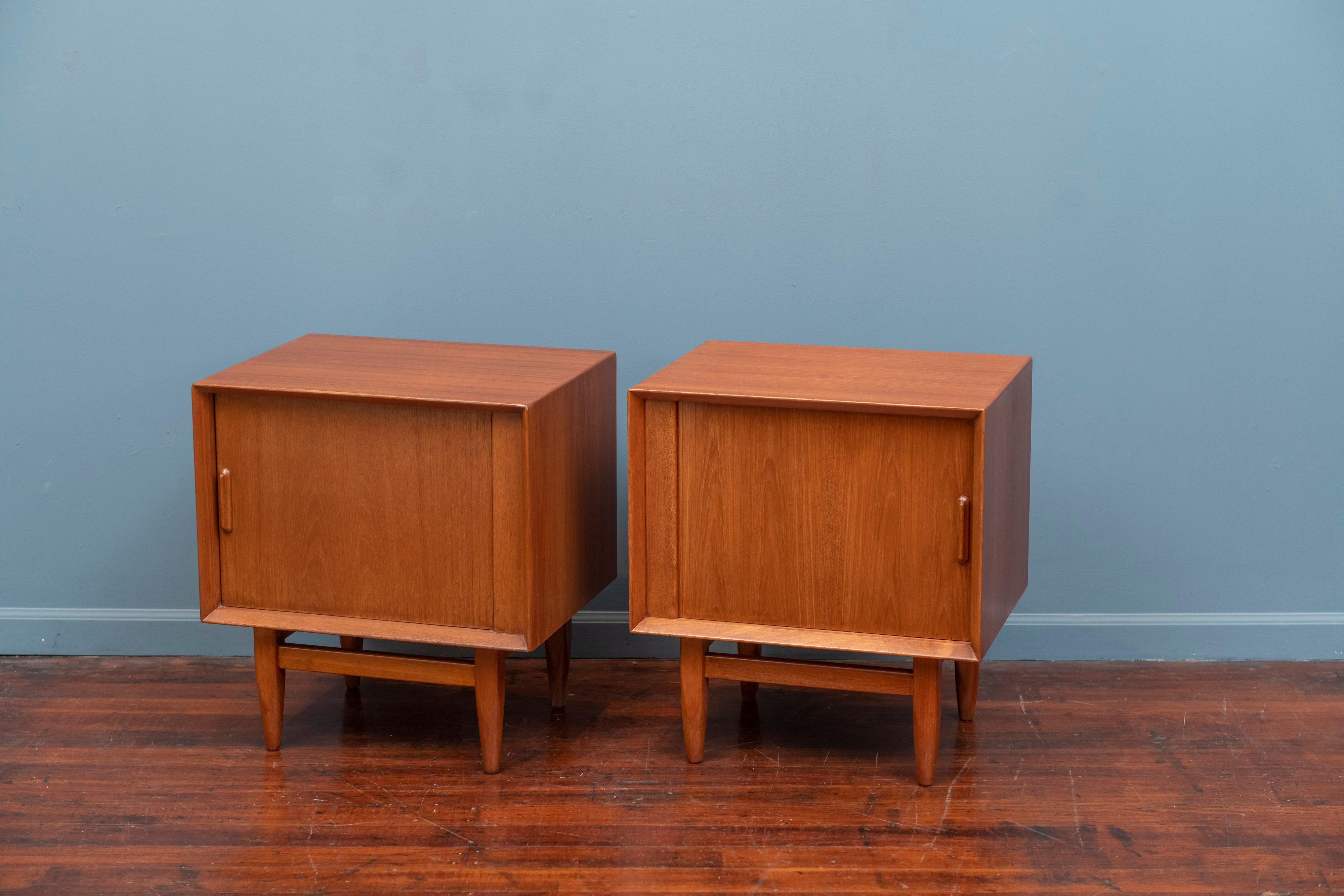 Scandinavian teak nightstands by Falster, Denmark. High quality construction and design made with a teak exterior and satinwood interiors each having a left and right sliding door, a single drawer and shelf. 
Newly refinished and ready to enjoy.