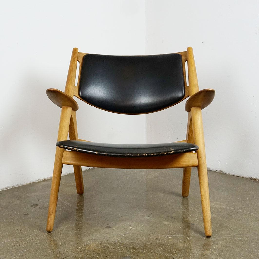 This iconic Scandinavian Lounge chair has been designed in the 1950s by famed Danish designer Hans Wegner and known universally as Sawback Chair. 
It is manufactured by Carl Hansen Denmark, Model No CH28.
This one is in beautiful original vintage