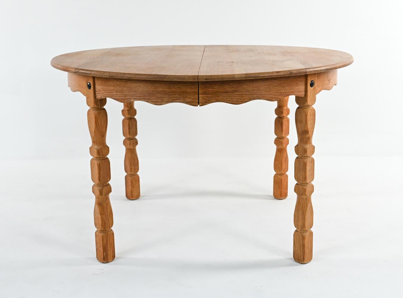 Constructed from beautiful quarter-sawn tiger oak, this Scandinavian dining table features a farmhouse-inspired round top and scalloped apron, with distinctive carved legs in the style of Henning Kjærnulf. This combination of traditional and modern