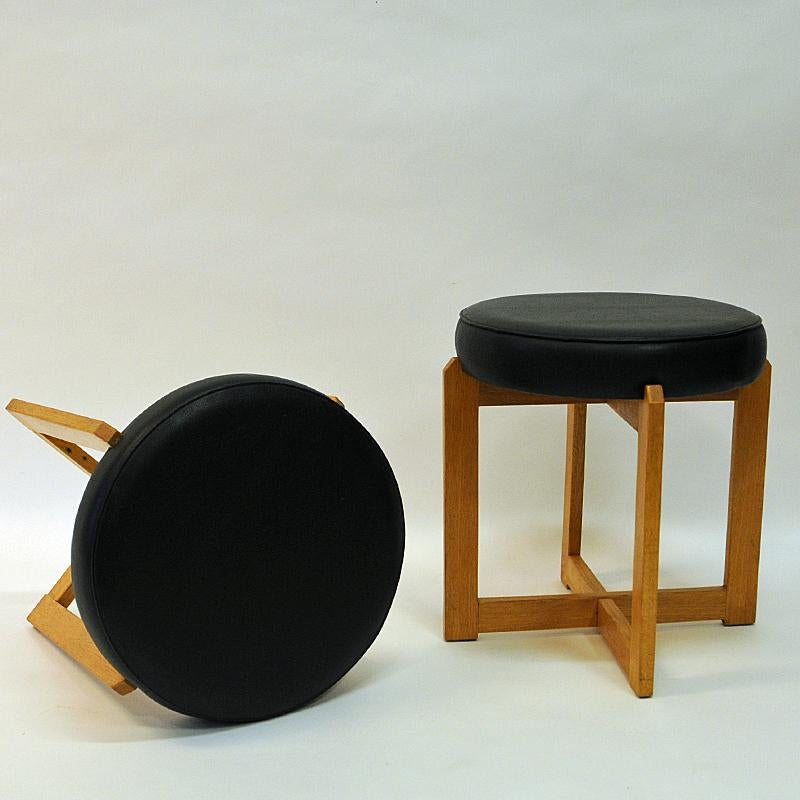 A great pair of solid oak stools/taburettes by Simpnäs Snickeri, Sweden 1960s. The stools have a round black leatherette cushion seat on top and solid square shaped legs in a cross design. Easy to store away and easy to use. Practical in every