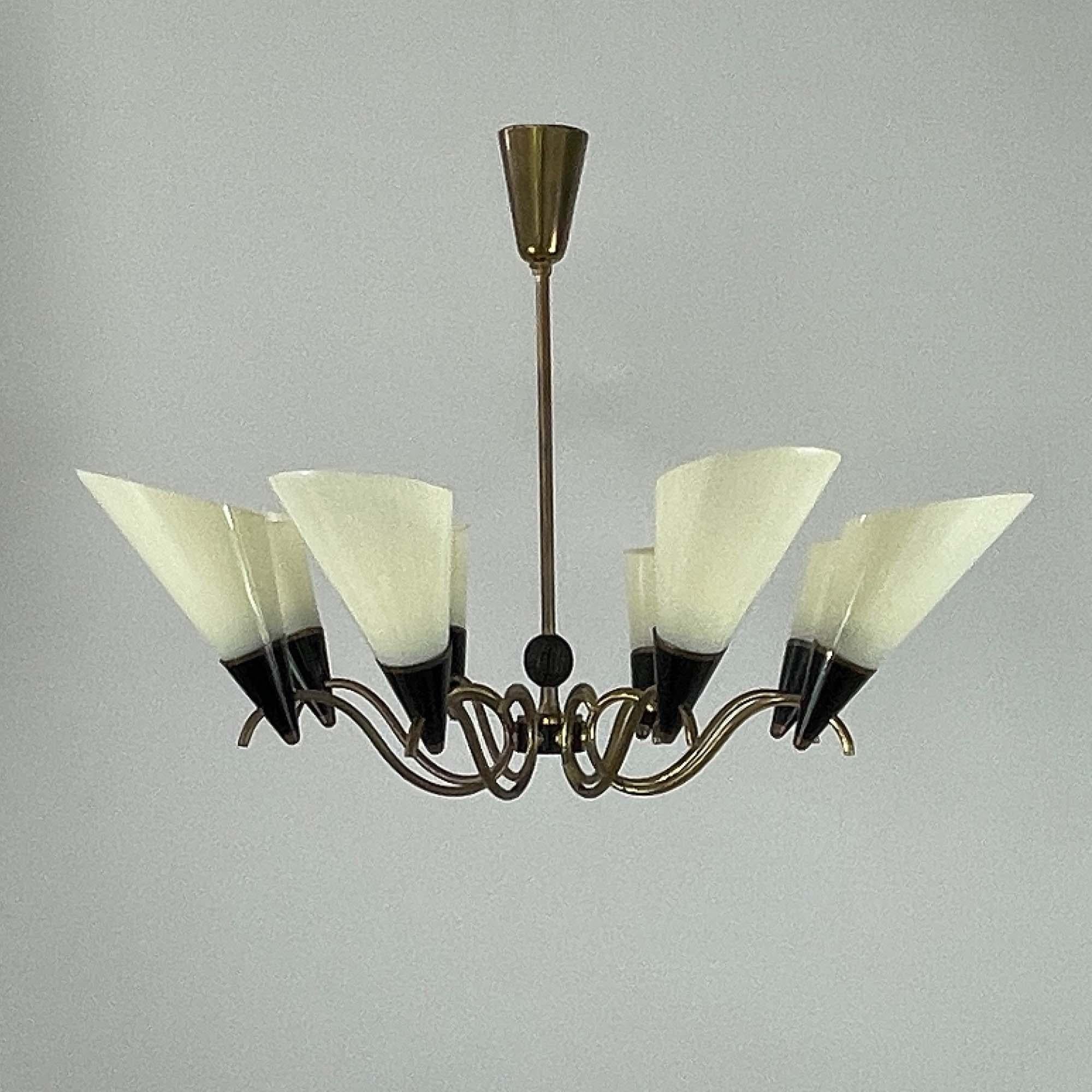 Cet élégant lustre du milieu du siècle a été conçu et fabriqué en Finlande dans les années 1950-1960.

Le luminaire comporte huit abat-jour coniques en verre opalin orientés vers le haut, chacun monté dans une douille noire qui ajoute du contraste.
