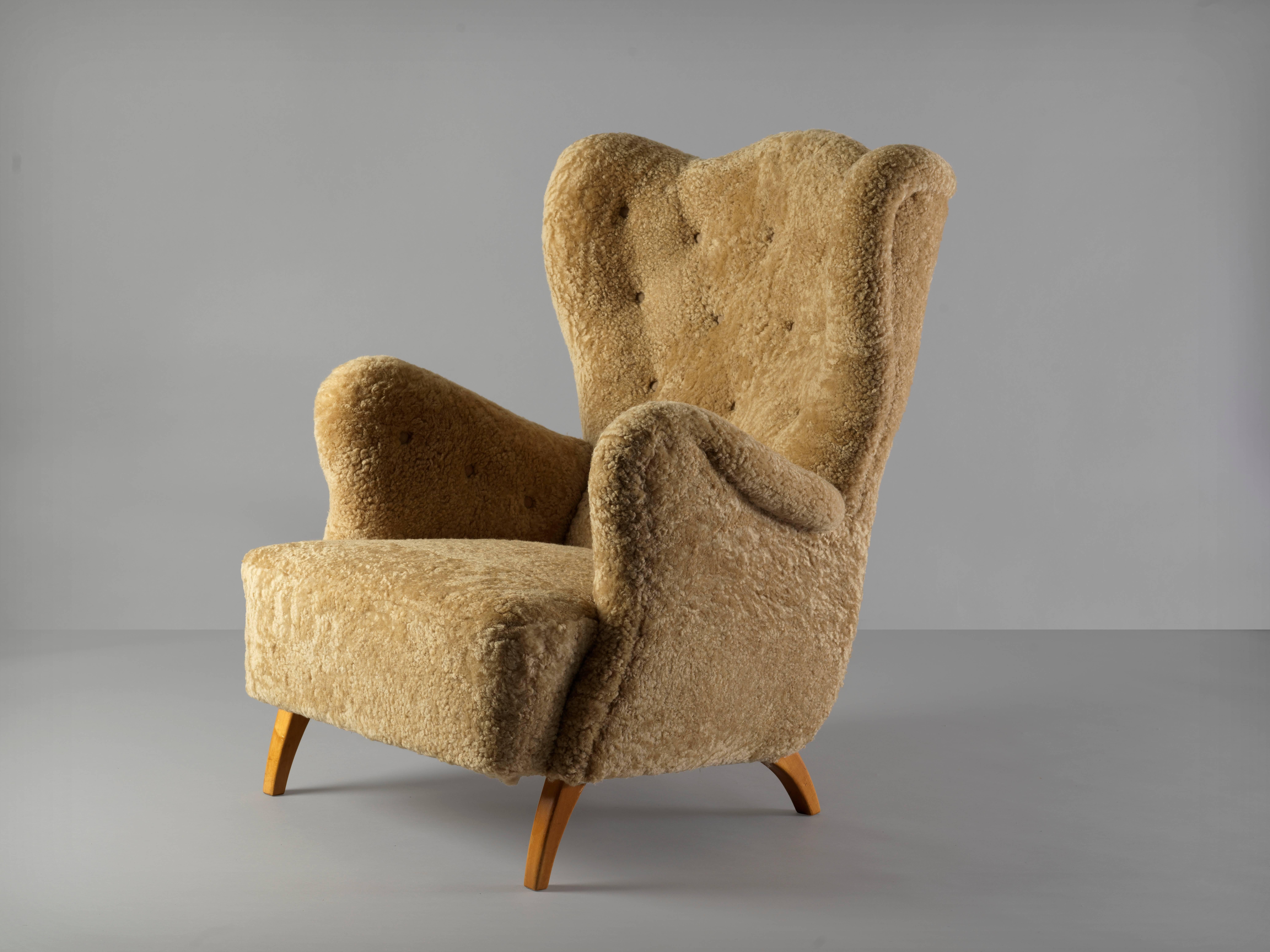 An early modernist lounge chair/armchair. Oak legs, reupholstered in beige lambskin / sheepskin. Produced in the 1940s in Scandinavia. Form in the manner of Peder Moos / Carlo Mollino. 

The chair presents the viewer with a lively organic