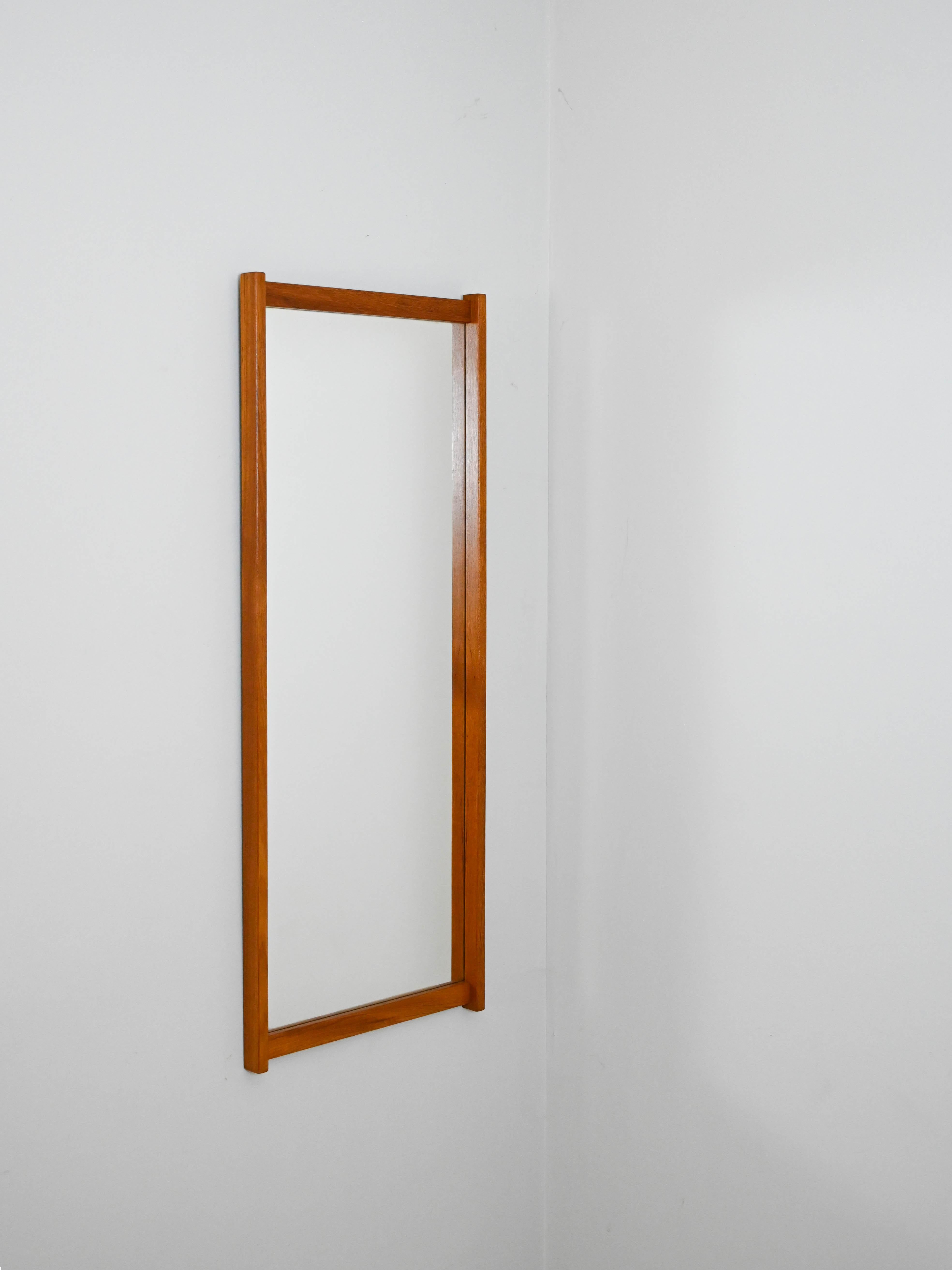 1960s mirror with a teak frame.

An elegant modern antique piece with a typical mid-century taste. It features a teak frame whose long sides are more prominent than the short ones, giving it an original look.
The minimal and timeless lines make