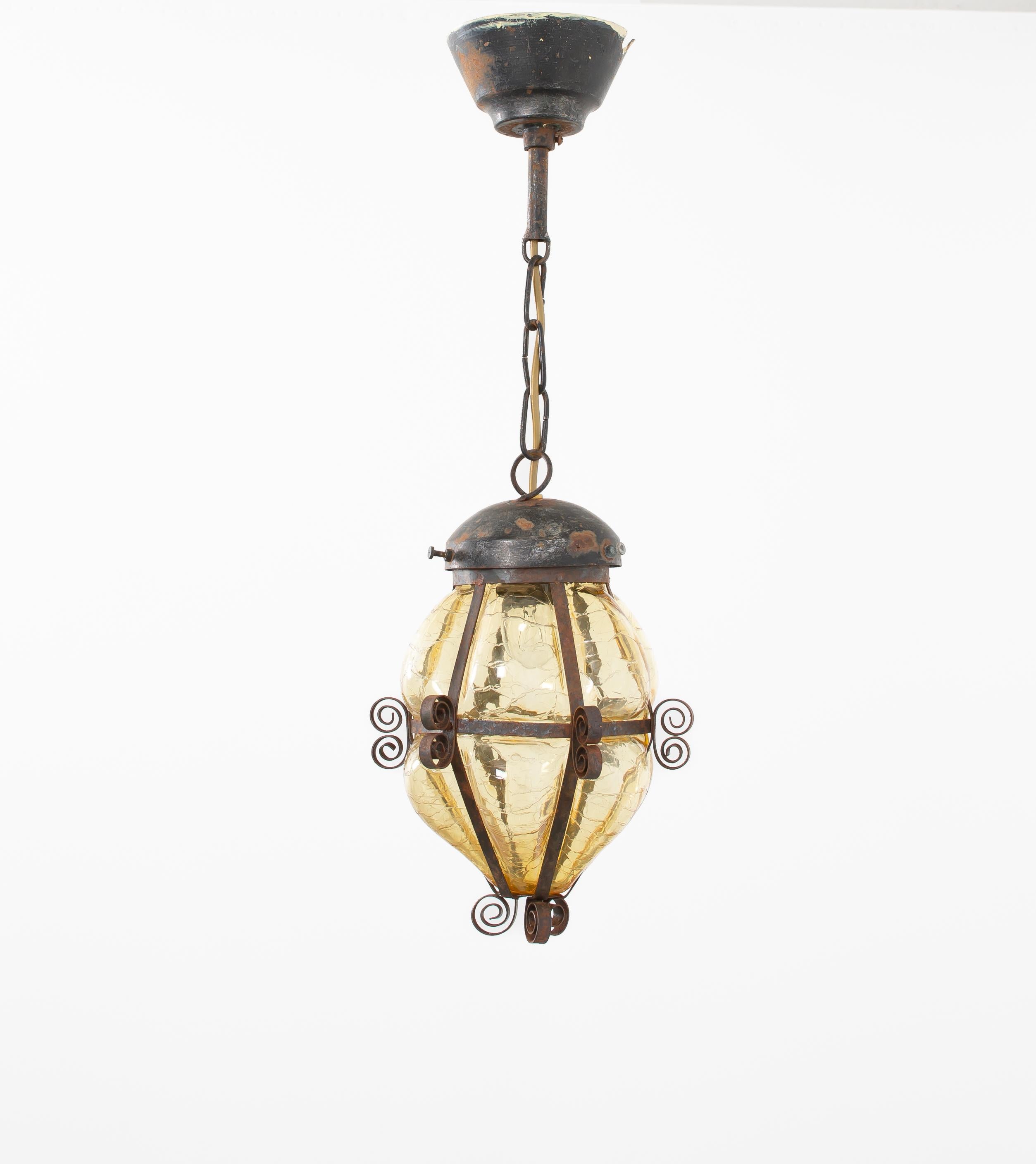 Lampada da soffitto scultorea e decorativa con paralume in vetro ambrato soffiato a mano, dalla texture morbida per diffondere la luce con un bagliore caldo e suggestivo. Il vetro è circondato da una cornice in acciaio goffrato e patinato, con