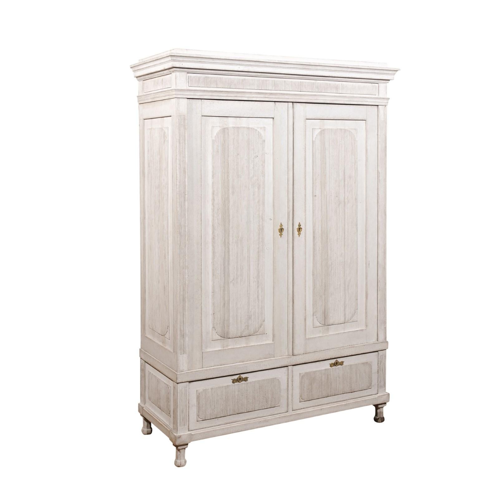 A Scandinavian painted wood wardrobe from the 19th century, with two doors, two drawers, reeded motifs and brass hardware. Made in Scandinavia during the 19th century, this stunning wardrobe features a beveled cornice sitting above two large doors